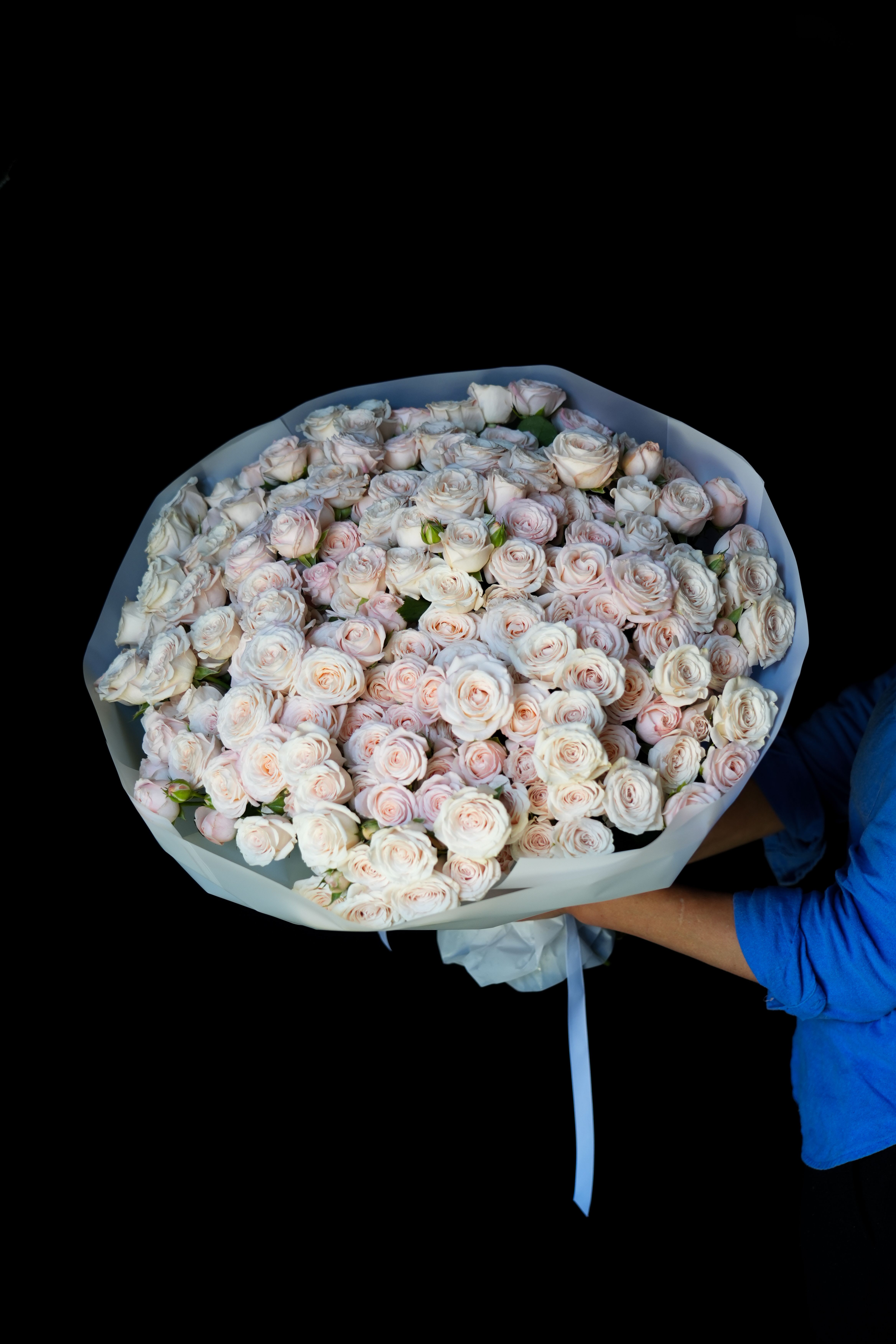 Fifty Shades Of White - Fifty Shades of White is the definition of timeless elegance. This breathtaking bouquet is composed of over 100 delicate blush and ivory spray roses, each one opening like a whispered love letter. Wrapped in crisp white designer paper and tied with satin ribbon, it's soft, subtle, and undeniably luxurious.  Whether you're celebrating a wedding, anniversary, or offering the most unforgettable “just because” moment, this bouquet delivers a message of purity, devotion, and refined beauty.  60 premium spray roses in shades of ivory, cream, and soft blush Hand-tied and wrapped in elegant white matte paper 