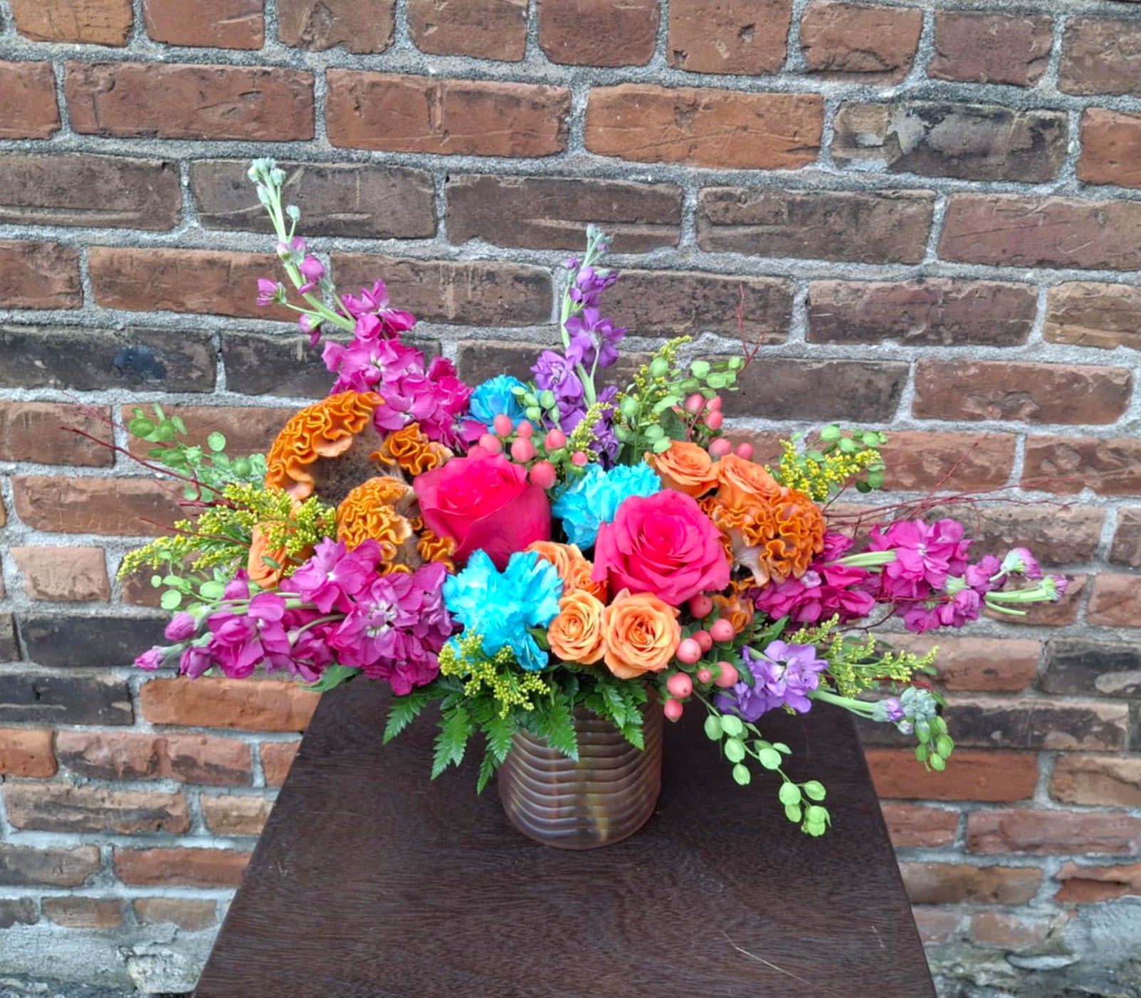 Coral Reef Coral Reef - Looking for a bright, summery bouquet, perfect for celebrating any of this season's festivities? Coral Charm is bursting with color and fun textural blooms! A mix of magenta and lavender stock, hot pink roses, orange spray roses, aqua carnations, celosia, pink hypericum, and yellow solidago are designed in a pink wave cylinder vase and accented with lush greens. Size Approx: 12" X 16"