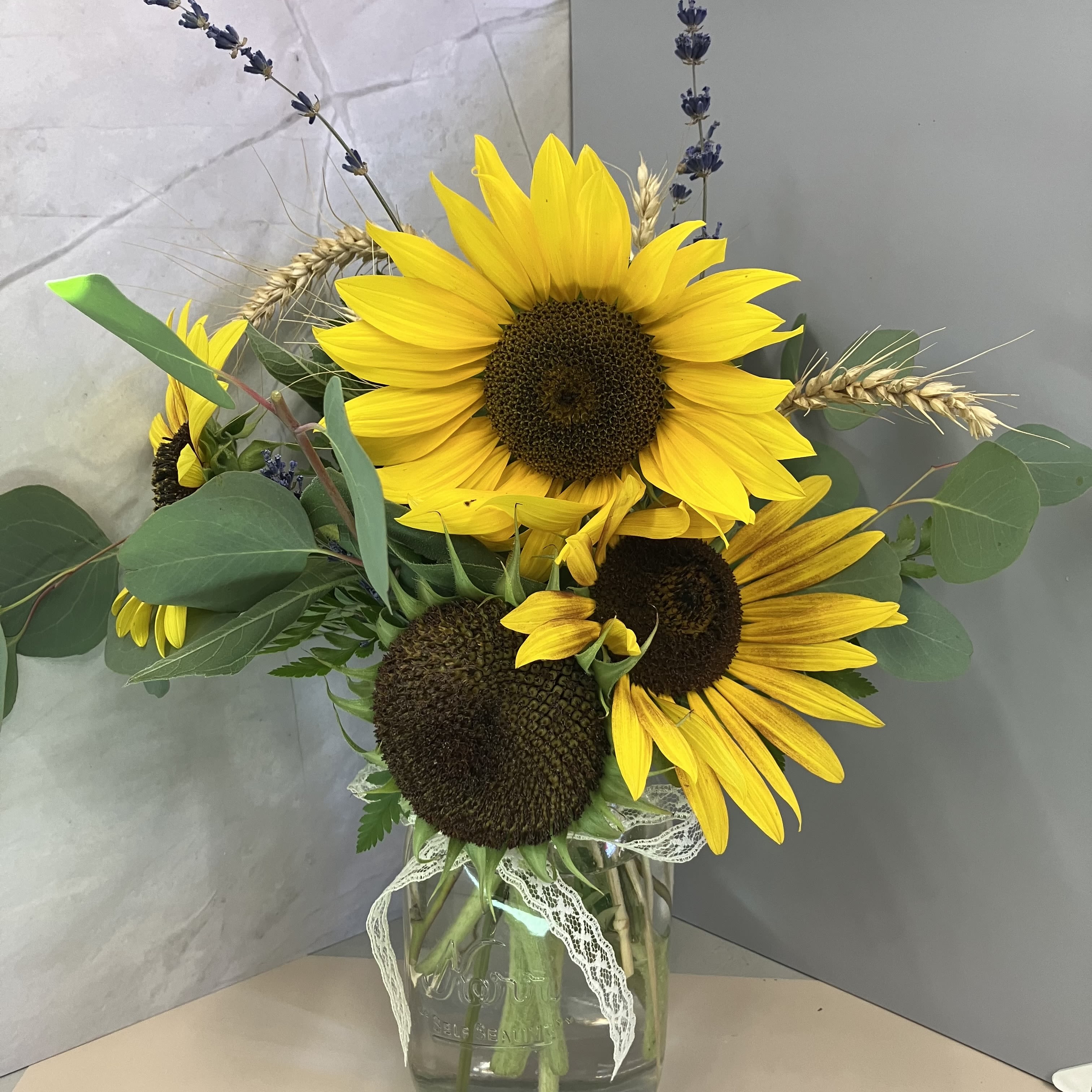 Walla Walla Harvest Mason Jar - Send a cute and cheerful mason jar arrangement of local sunflowers and wheat. Accented with lavender and a lace bow! 