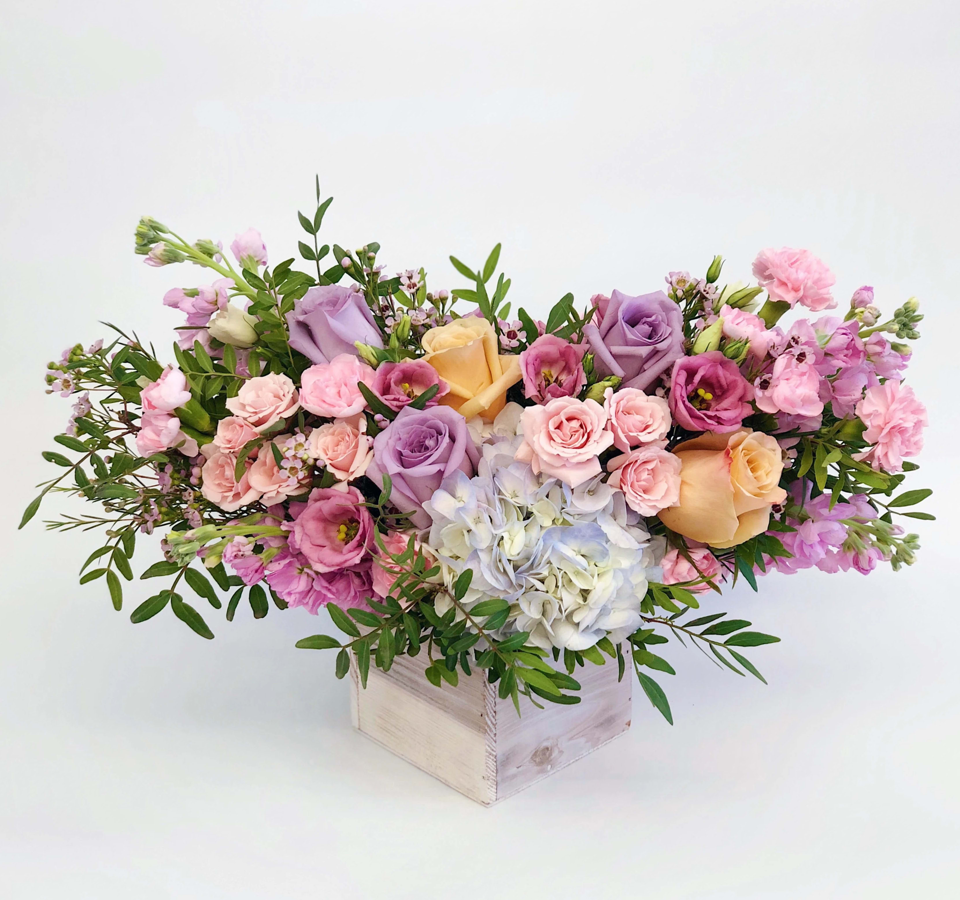 #86 - Garden Style Arrangement In Wood Box Lavender And Peach #86 - Garden Style Arrangement In Wood Box Lavender And Peach - Mixed flowers, from romantic and gentle to an edgy and interesting look. If You want a bouquet with a twist, choose our flower boxes. We have wood boxes for rustic-looking arrangements or hat boxes for a more elegant look. It’s a beautiful and convenient way. Flowers in boxes don’t need vases. That makes it perfect for transportation and keeping flowers hydrated and secure.