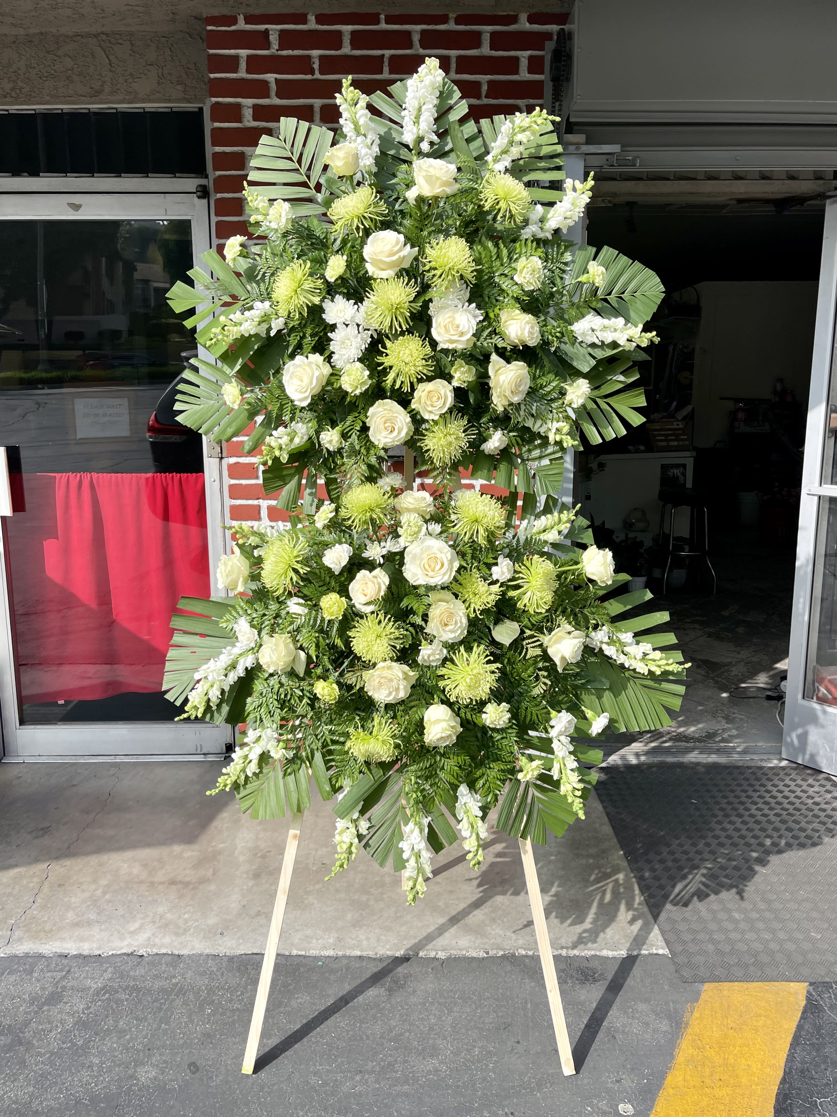 Korean Traditional Double Sympathy Standing Spray - Green Korean Traditional Double Sympathy Standing Spray - Green - Show support for your loved ones with this fresh, green standing spray. The long, customizable banners allow you to both send your message of comfort, and easily let your loved ones know who is supporting them. The banners are carefully placed so that both the beauty of the flowers and the warmth of your heart shine through. This stunning arrangement includes a green and white variety of roses, chrysanthemums, carnations, and snapdragons with a backdrop of commodore and other greenery. To make the arrangement as fresh as possible, flower colors and varieties may vary based on seasonal availability.