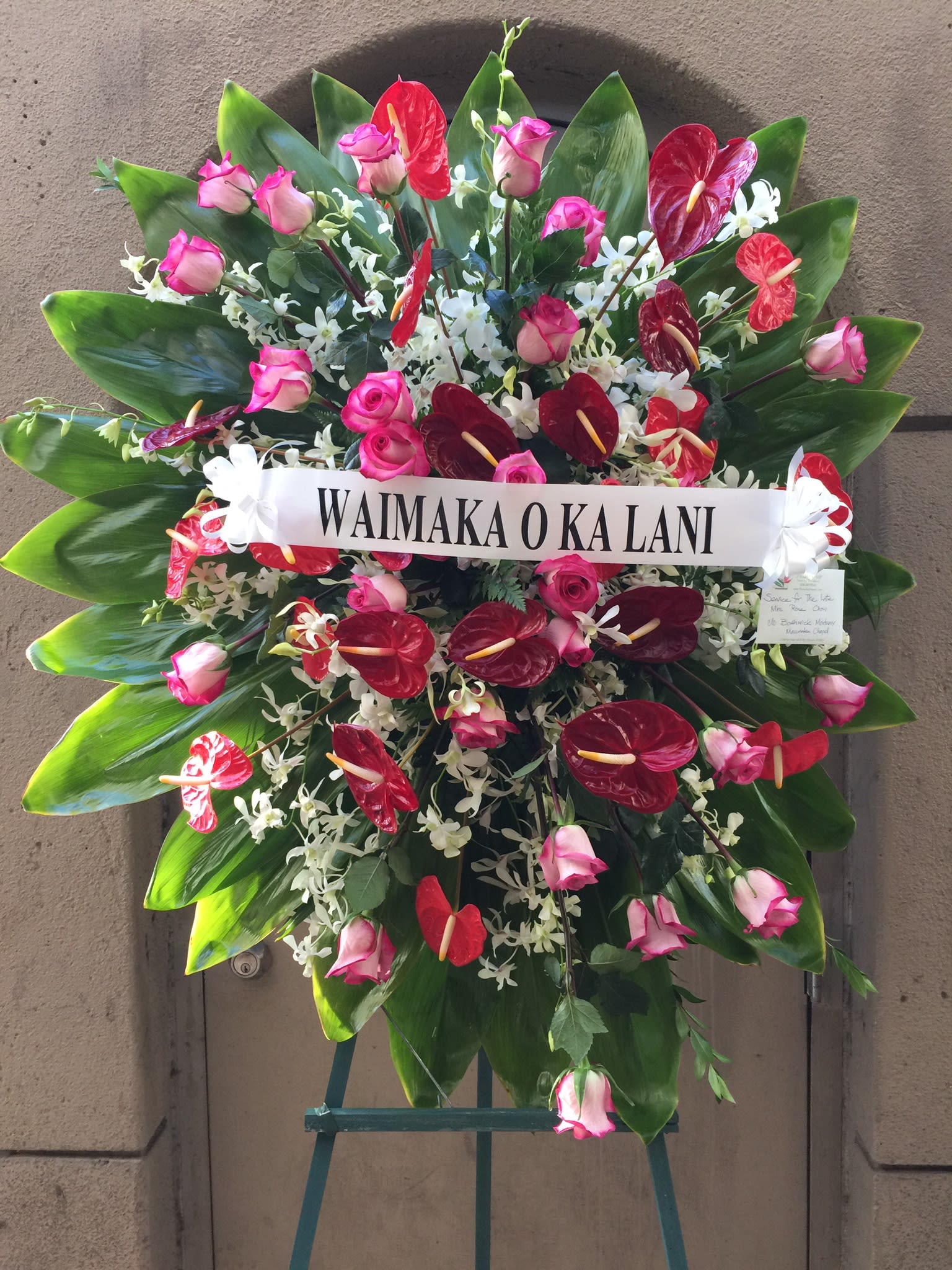 Vibrant Red Anthurium and Pink Roses Wreath - F200W04 - Sunburst of pink roses and red antherium intermingled with sprays of white orchids, surrounded by lush green ti leaves