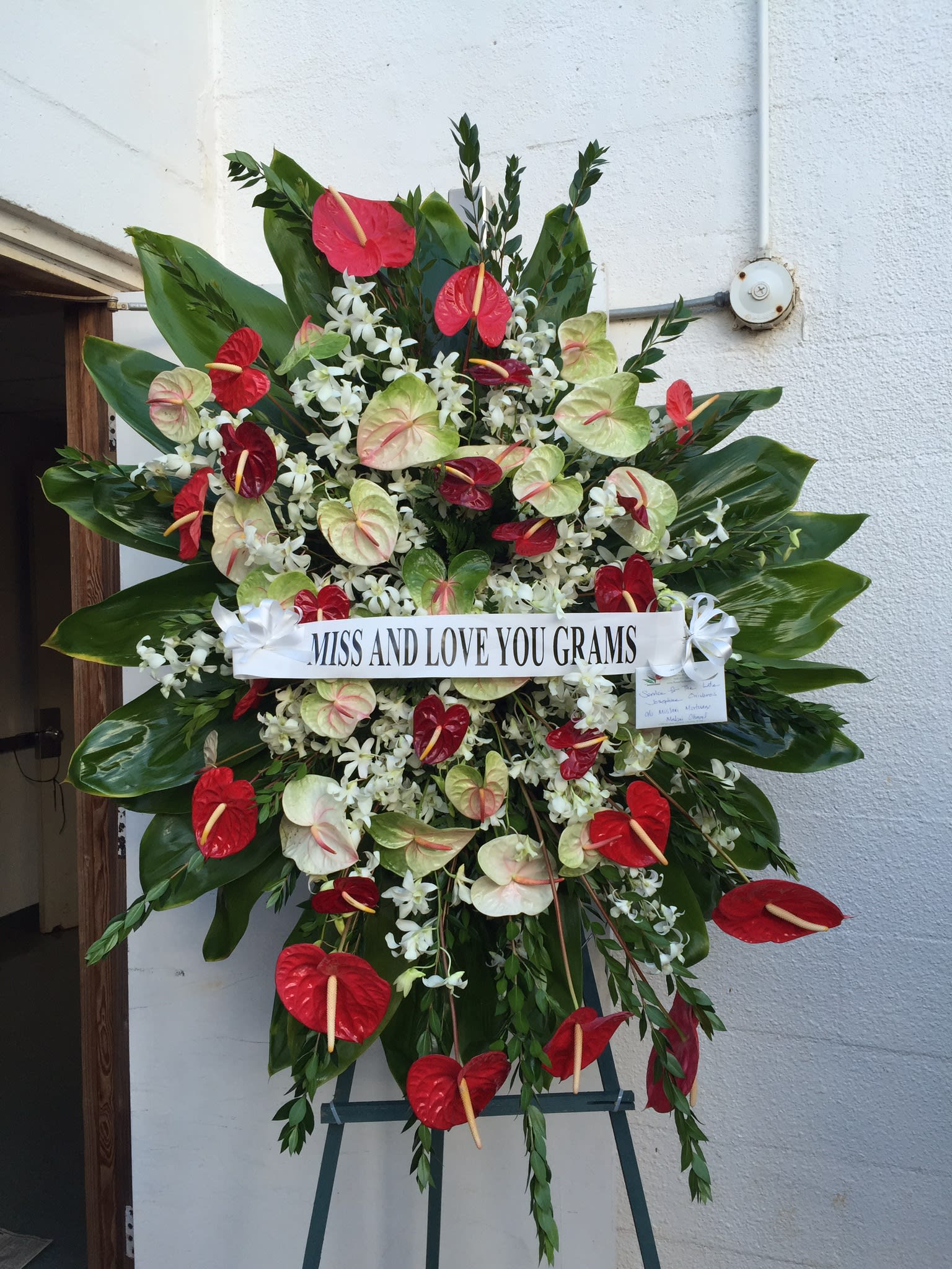 Colorful Tropical Wreath - F200W02 - Colorful mix of Antherium intermingled with sprays of white orchids, surrounded by lush green ti leaves. 