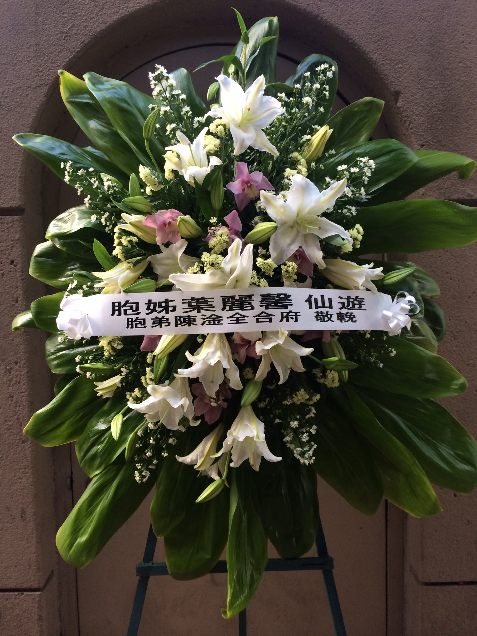 White Lilies with Cymbidium and Orchid Spray Wreath - F175W07 - Spectacular display of white lilies with dendrobium orchids adding softness and elegance. Green ti leaves surround and small sprays of white daisies completes the wreath. 