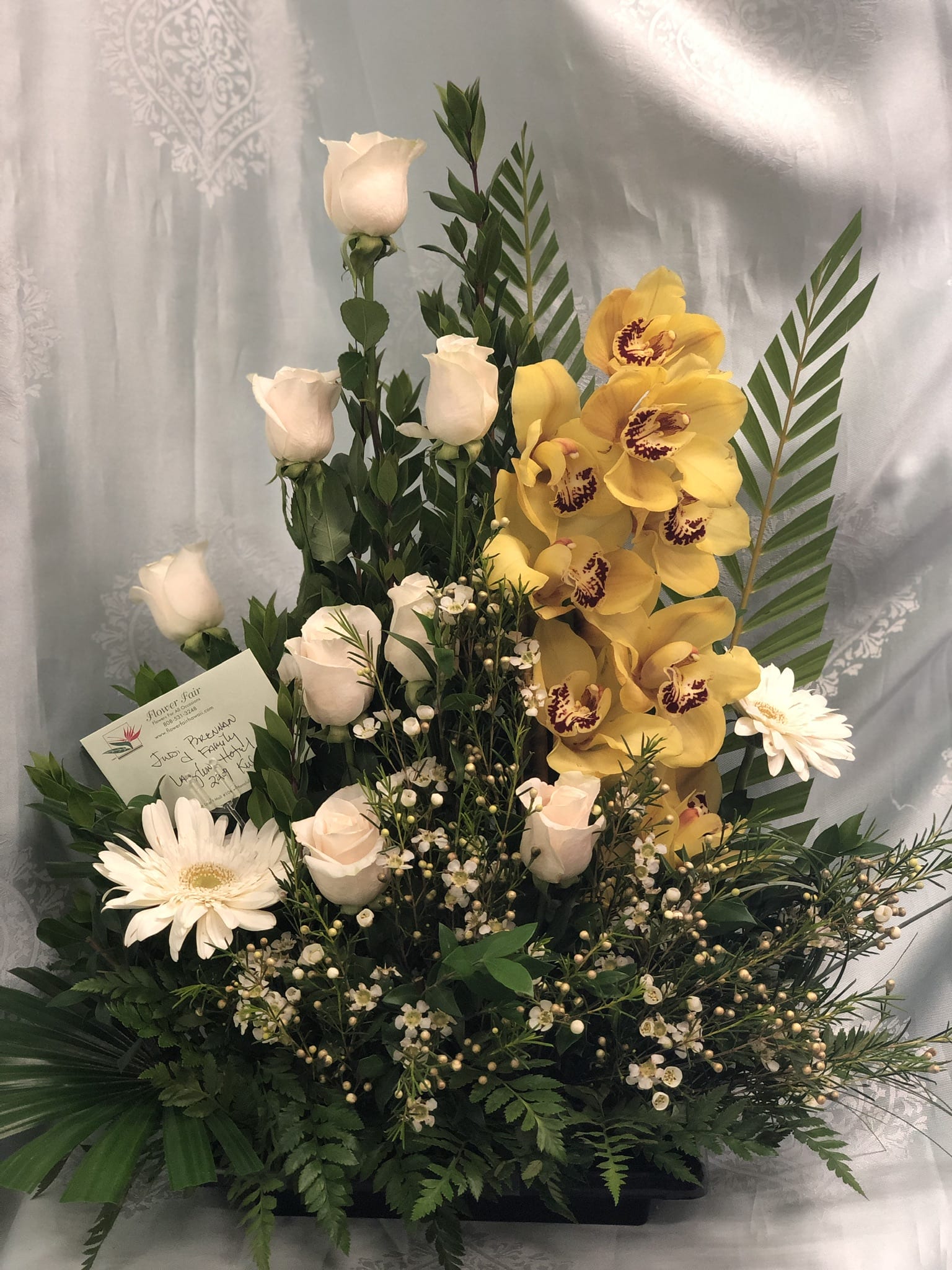 Pure Elegance - E30050 Pure Elegance - E30050 - Lovely arrangement with white roses, yellow cymbidium orchids, accented with white gerbera daisies.