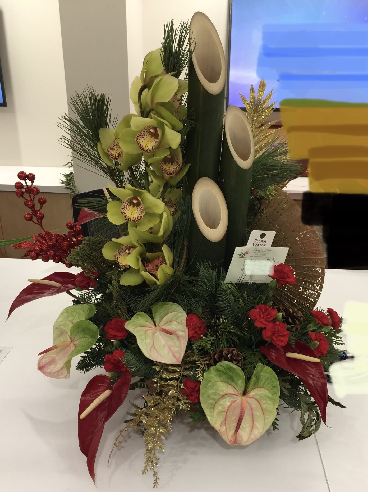 Fancy Cymbidium orchid &amp; tropical Kadomatsu - Grand and full of impact!  This beautiful arrangement with Cymbidium, Antherium, holiday sparkles and stately Kadomatsu bamboos with an oriental fan for extra flare.