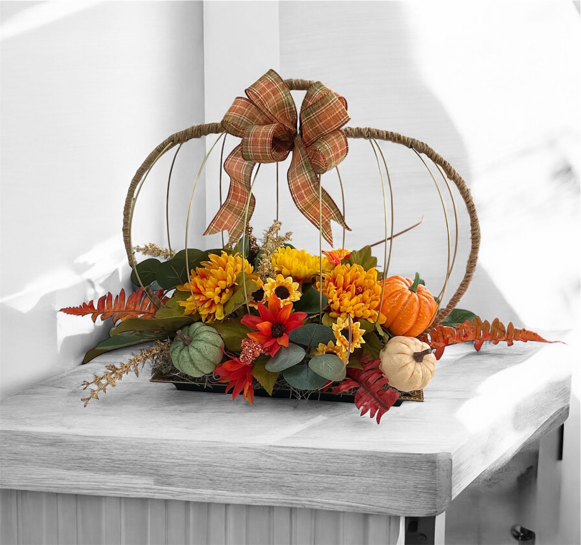 Autumn Harvest Silk Pumpkin Centerpiece - Bring the warmth of fall to your home with our Autumn Harvest Silk Pumpkin Centerpiece ! This charming centerpiece features a wicker pumpkin-shaped frame adorned with a cozy plaid bow, filled with vibrant yellow and red flowers, lush greenery, and decorative mini pumpkins in autumn hues. Perfect for decorating your dining table, mantle, or entryway for Thanksgiving or any fall gathering. Adds a touch of rustic elegance to your seasonal decor.
