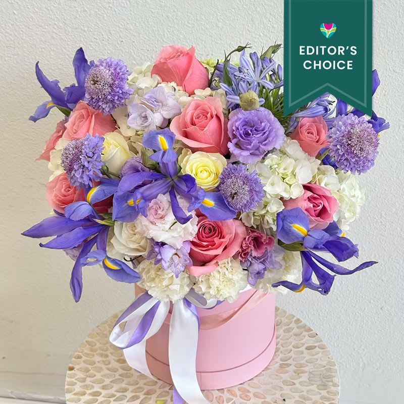 Iris Garden - Editor's Choice - A radiant burst of seasonal charm, this signature vase arrangement from Lotus Event Decor features a joyful blend of pink peonies, garden roses, lisianthus, blue delphinium, chamomile, and wildflower accents. Designed in a classic clear glass vase, the bouquet evokes the feeling of a fresh-cut garden — soft, romantic, and effortlessly elegant.    Perfect for birthday flowers, Mother’s Day, housewarming gifts, or a just-because floral delivery, this bouquet adds warmth and beauty to any space. Its organic style and pastel palette make it an ideal choice for both modern interiors and special celebrations.