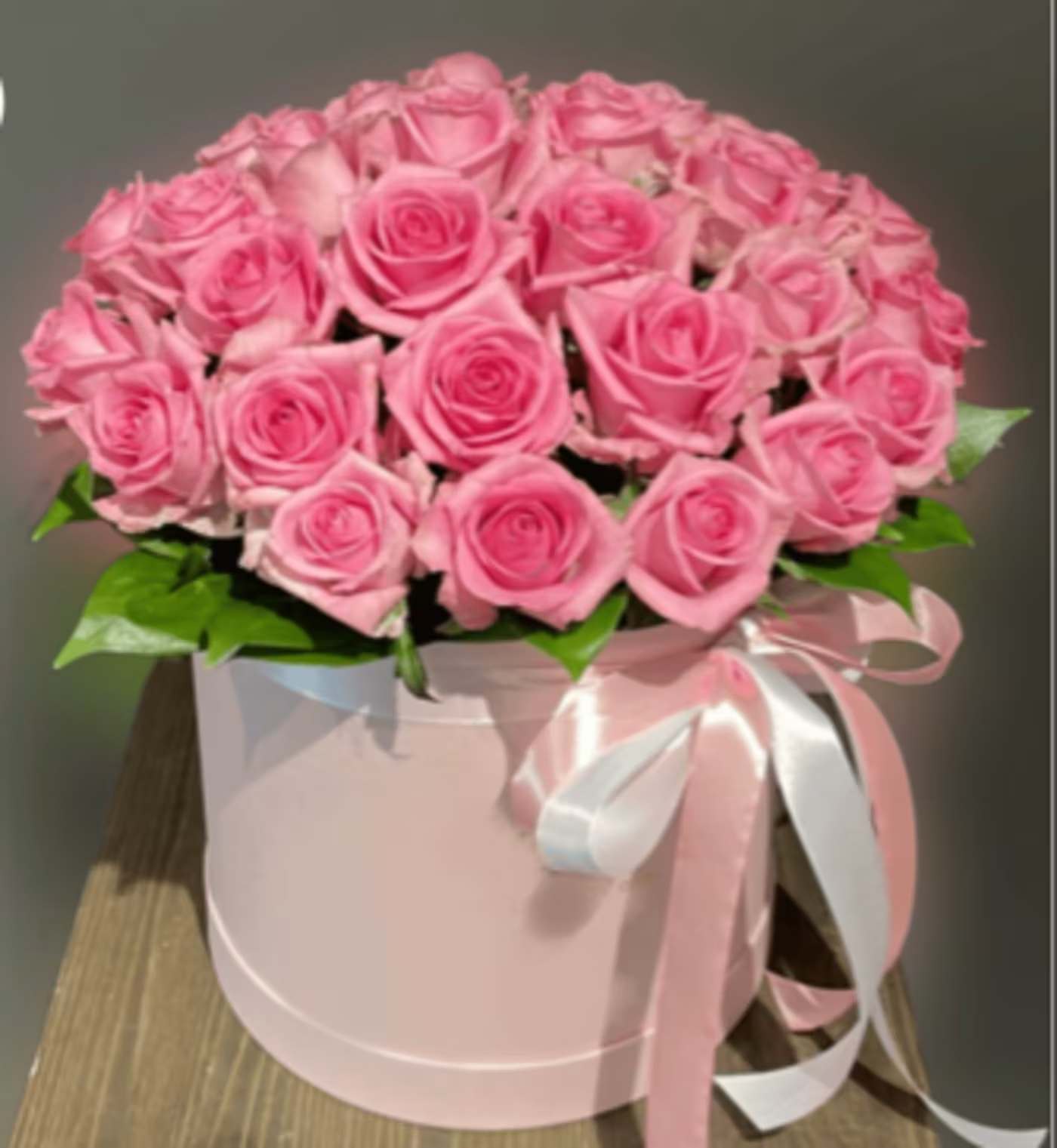 Blush Pink Roses in a Box - Delight in the timeless elegance of this luxurious arrangement of blush pink roses, a perfect gift for expressing love, appreciation, or admiration. Each rose is carefully selected for its flawless bloom and soft, romantic hue, ensuring a stunning and sophisticated presentation. Nestled in a chic pink round box adorned with an elegant satin ribbon, this arrangement exudes class and beauty, making it an unforgettable gift for any special occasion.  Whether you're celebrating a birthday, anniversary, Valentine's Day, or simply wishing to surprise someone with a thoughtful gesture, this floral design is a perfect choice. Its soft pink tones and lush greenery create a harmonious blend that radiates elegance and charm. The sophisticated packaging elevates the presentation, making it ideal for creating lasting memories. 