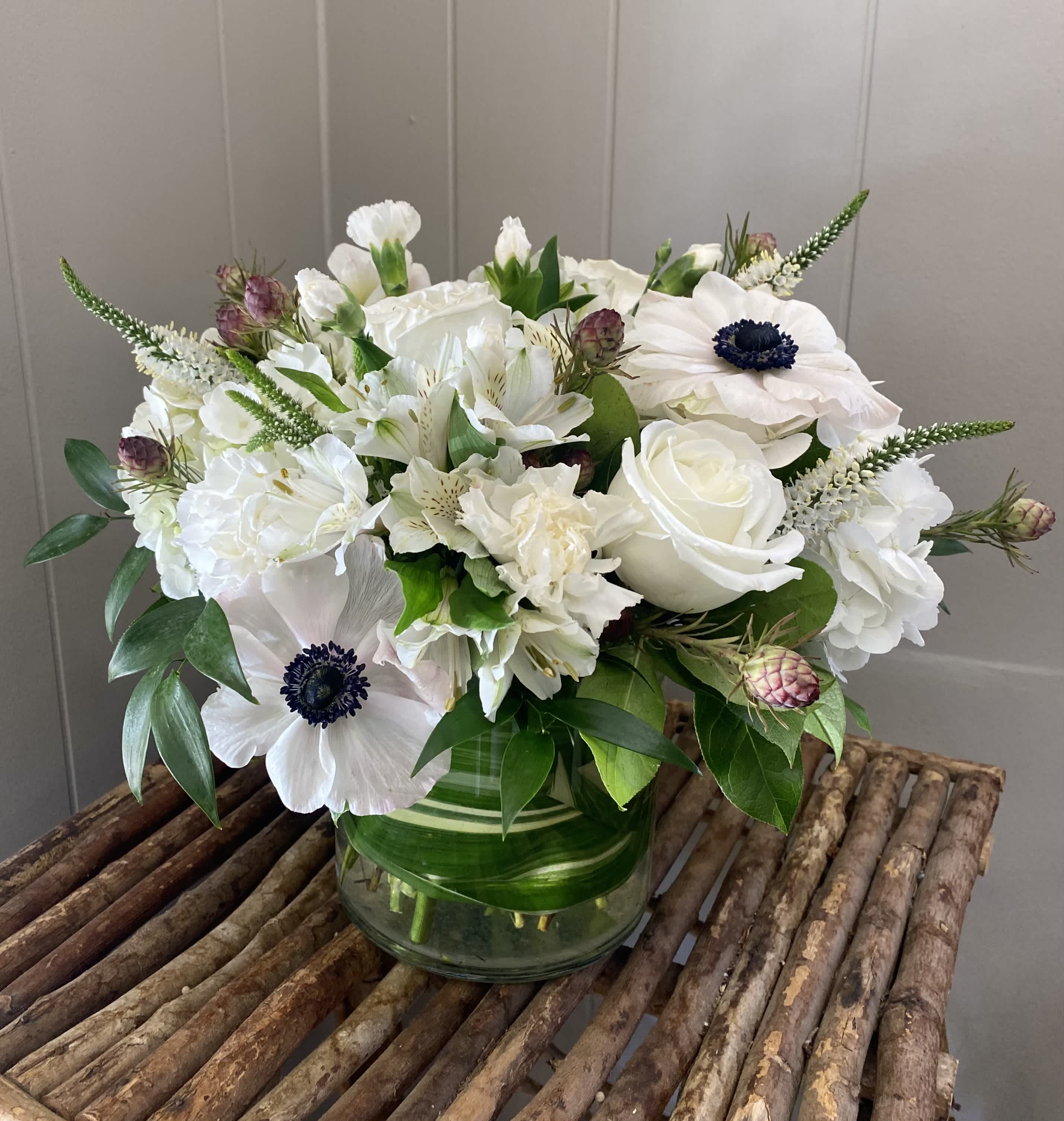 Moonstone - Up in the sky or on the ground, this arrangement is sure to delight! Featuring white roses, hydrangea, anemones, and white filler.  