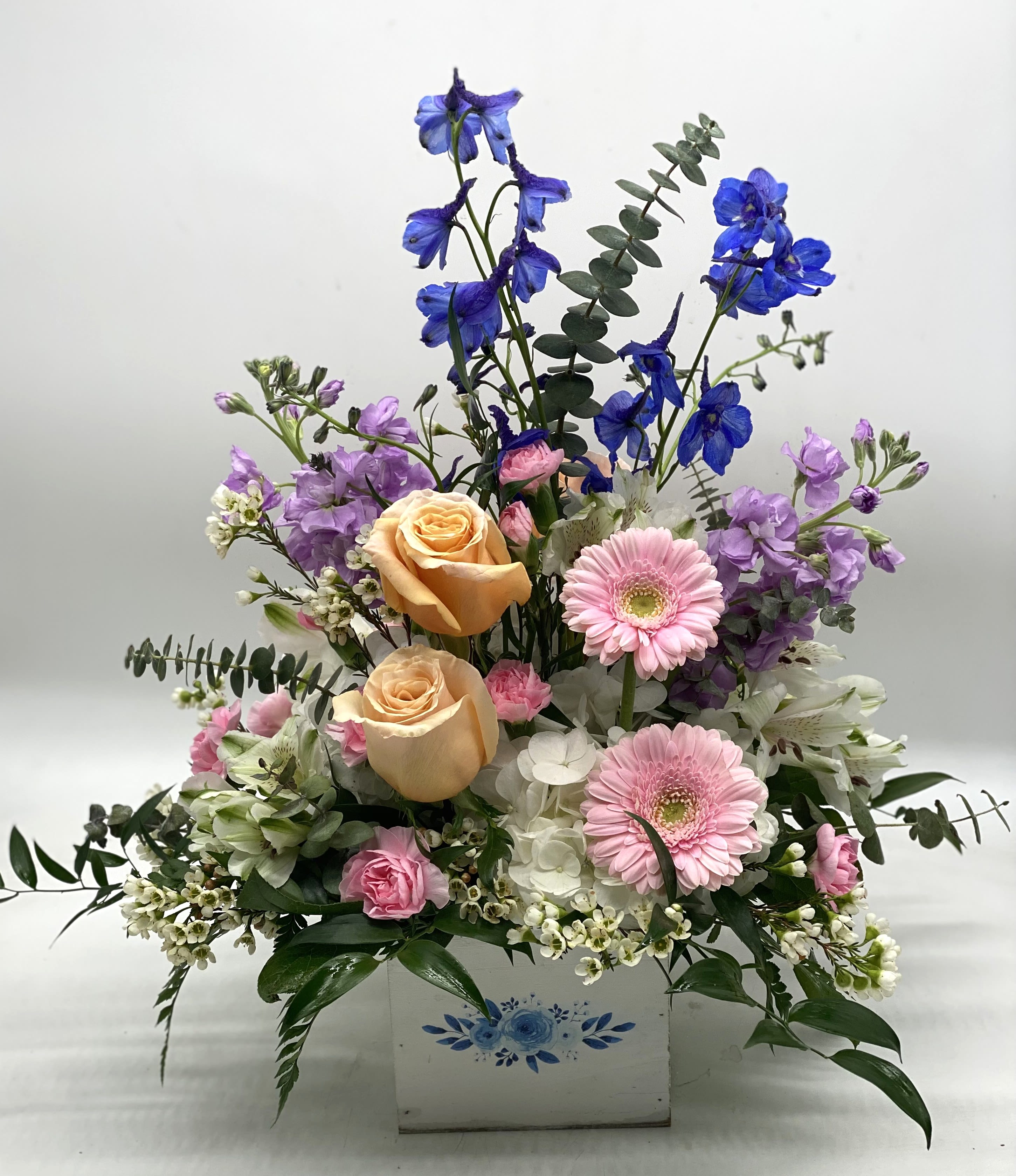 Blue Bloom Box - A soft pastel blend of fresh flowers designed in a white wooden box with blue floral embellishment. 