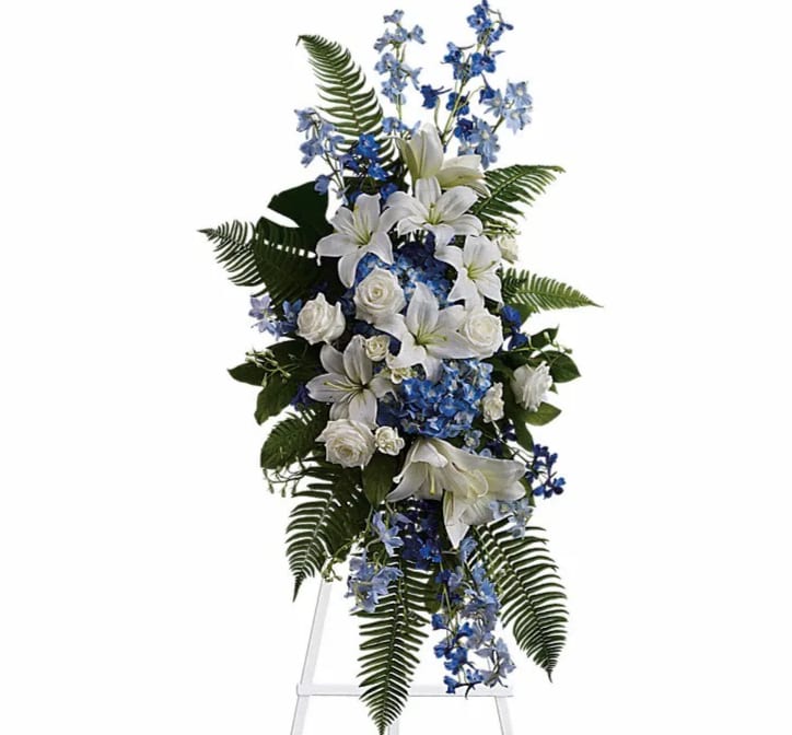 Ocean Breeze Spray - Express deep condolences and strong hopes for the future with an elegant tribute that conveys admiration affection and respect. Lovely flowers such as white asiatic lilies and roses blend with blue delphinium and hydrangea set amidst ferns.