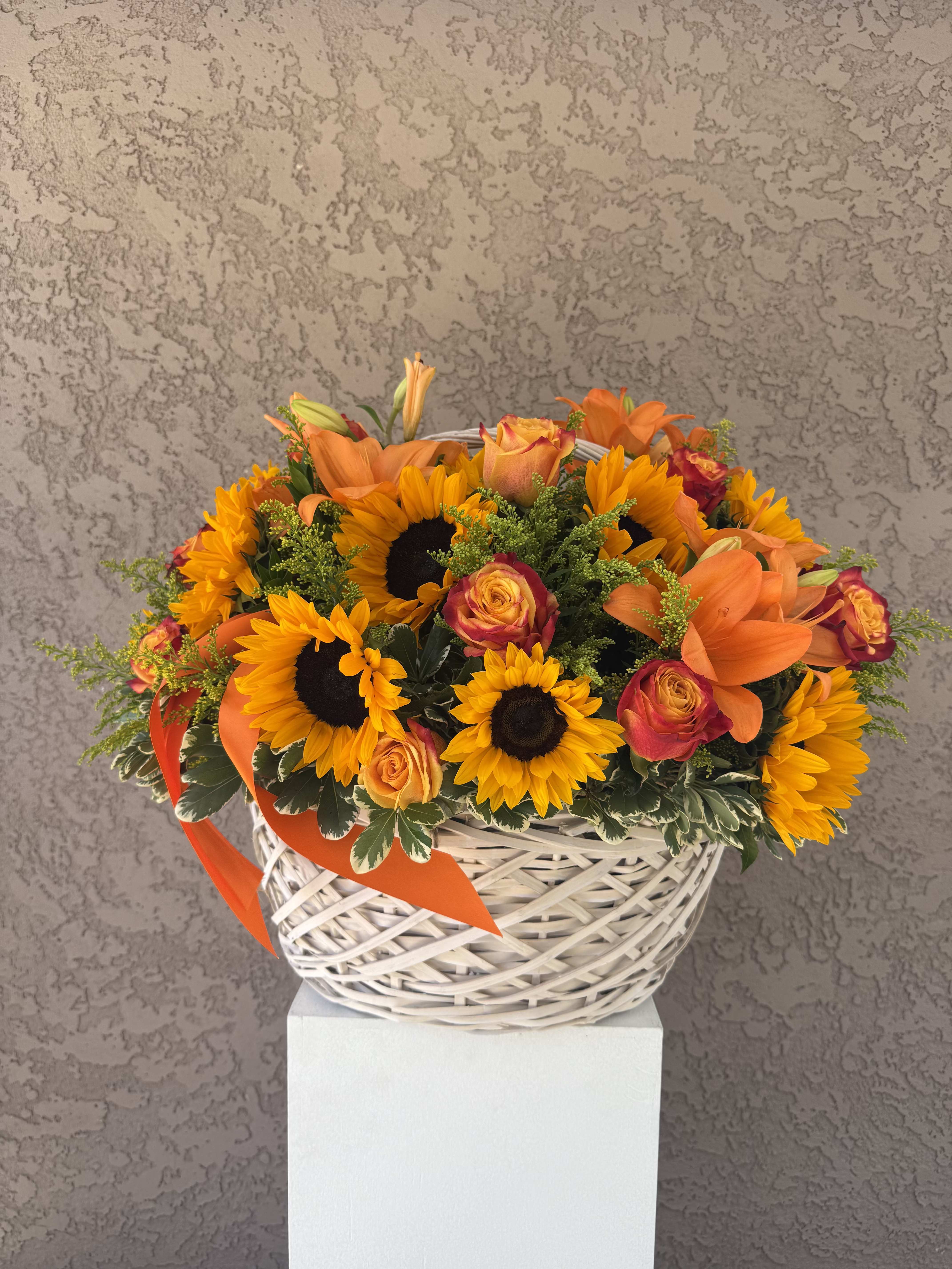 Basket Full of Sunshine - Overflowing with golden hues and joyful blooms, Basket Full of Sunshine features sunflowers, orange lilies, fiery bi-color roses, and lush foliage arranged in a charming white wicker basket. Designed in Beverly Hills, CA and available for same-day delivery throughout Los Angeles, this festive arrangement is perfect for birthdays, thank-yous, housewarmings, or fall-inspired gifting. Handcrafted by Family Tree Flower — your local Beverly Hills florist offering vibrant, heartfelt floral design delivered across LA.  Sunflowers – Joy, positivity, adoration Orange Lilies – Passion, energy, confidence Orange &amp; Red Bi-Color Roses – Enthusiasm, admiration, and warmth Solidago (Goldenrod) – Good fortune, encouragement, and cheer