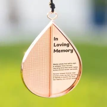 In Loving Memory Boxed Wind Chime - This elegant 28-inch wind chime The Wind Chime Company offers a timeless way to honor a loved one. Crafted from anodized aluminum with a rose gold finish, its soft, melodic tones bring peace and remembrance to any space. The unique dome top and delicate heart-themed sail create a graceful silhouette—perfect for indoor display or outdoor serenity.  Each chime is presented in an elegant gift/display box, making it equally meaningful when received as a sympathy gift   What’s Included:   * A heart-shaped circular sail with a charm that can be personalized with names, dates, etc by the recipient   * A beautiful 5x7” memorial card—ready to frame or place anywhere at home   * A premium “Thinking of you” envelope, ideal for handwritten condolences or gift messages   * A convenient slide-to-mute feature for quiet moments of reflection &quot; Chime 