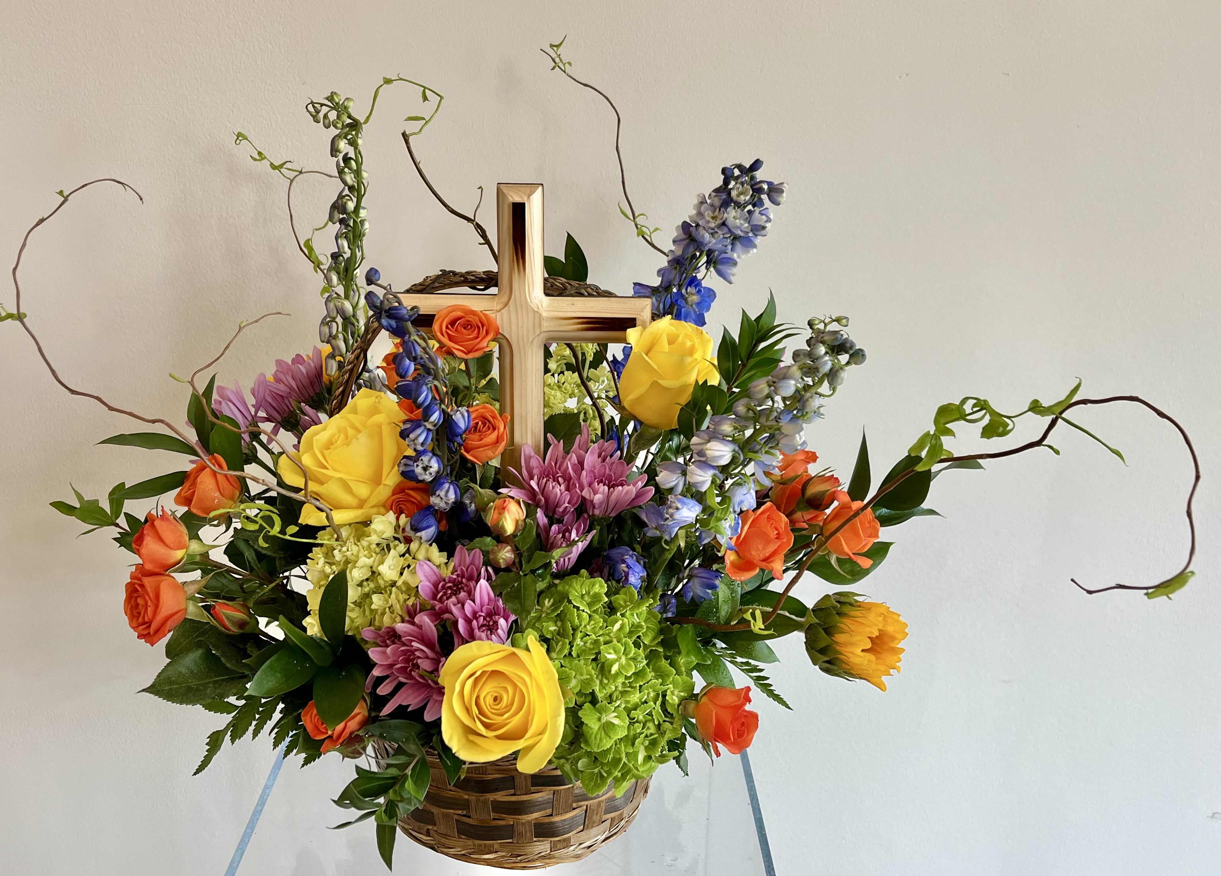 Heavenly Joy - A beautifully bright floor basket is captured in this stunning arrangement with an adorned cross. Each gorgeous bloom is designed to bring solace during difficult times.   Designed for display. For long lasting blooms add water daily.