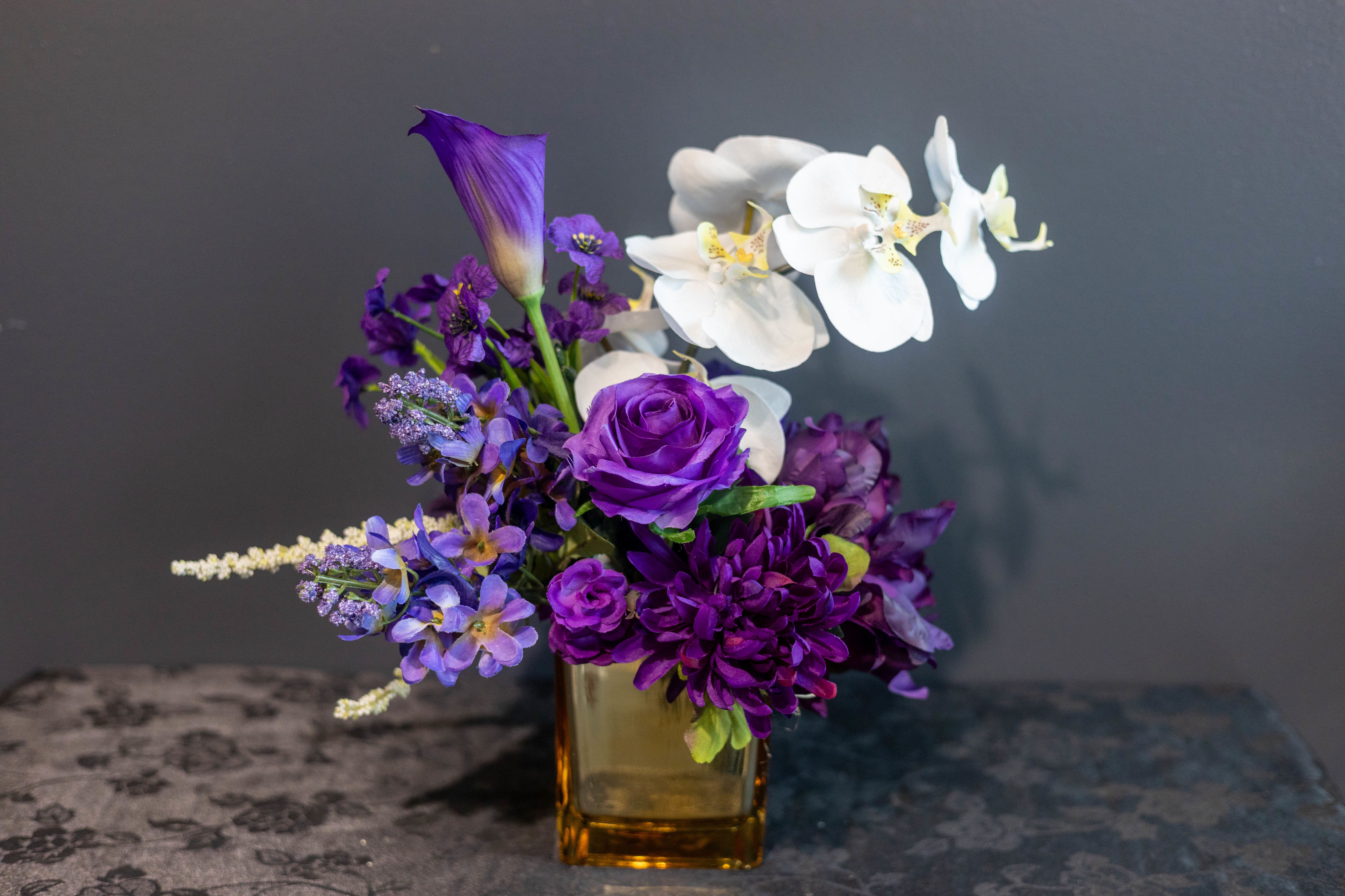 Purple Rain - Faux Flowers - A poetic tribute to a life beautifully lived, &quot;Purple Rain&quot; evokes grace, reverence, and lasting peace. This lush, permanent arrangement features a stunning cascade of deep purple roses, symbolizing dignity and eternal love, interwoven with pure white orchids, representing serenity and a gentle farewell.