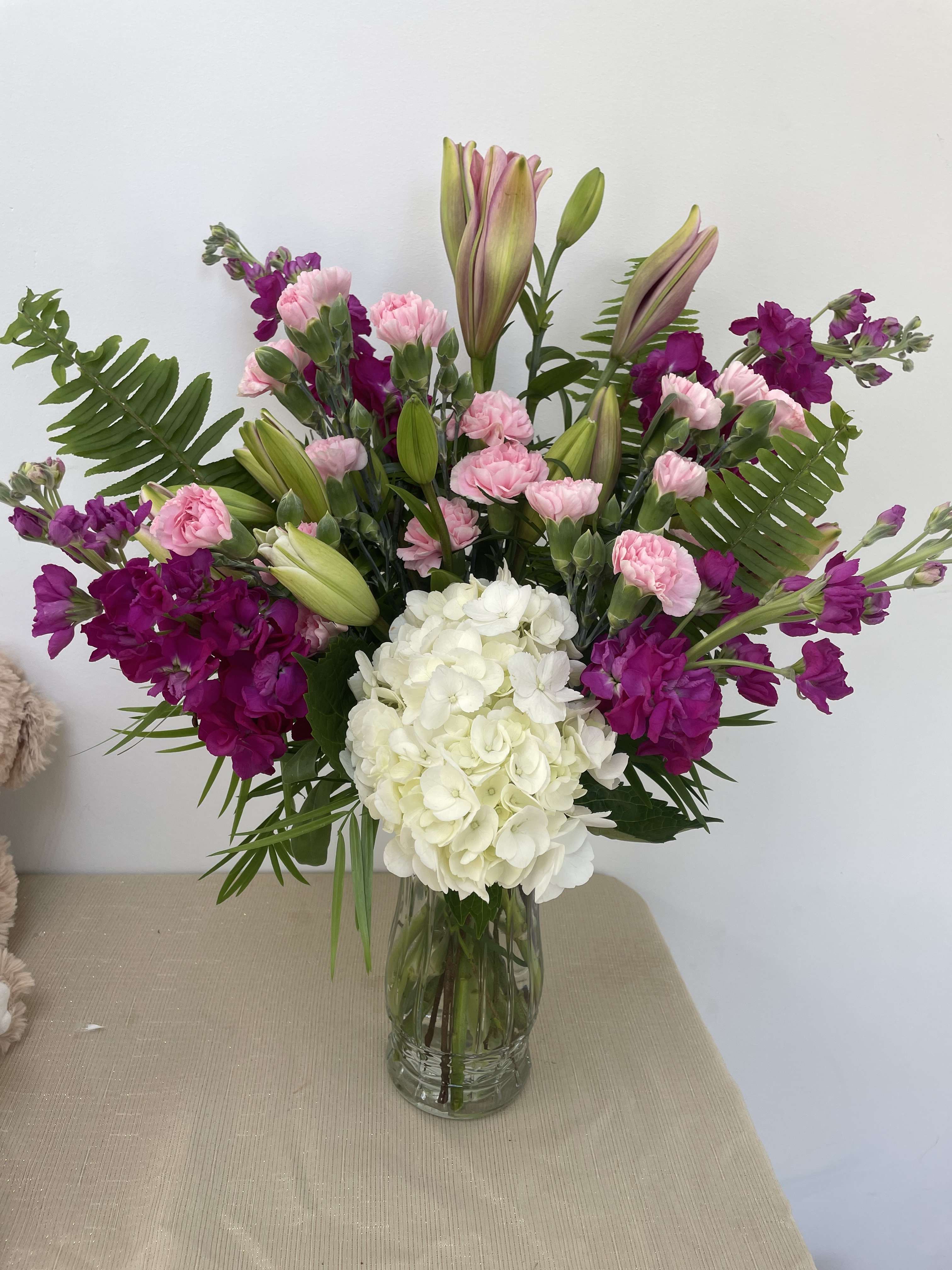Lovely Lavander and white Lovely Lavander and white - White and Lavander tones in a vase. Hydrandea, Lilies, stock and carnations in a clear vase.