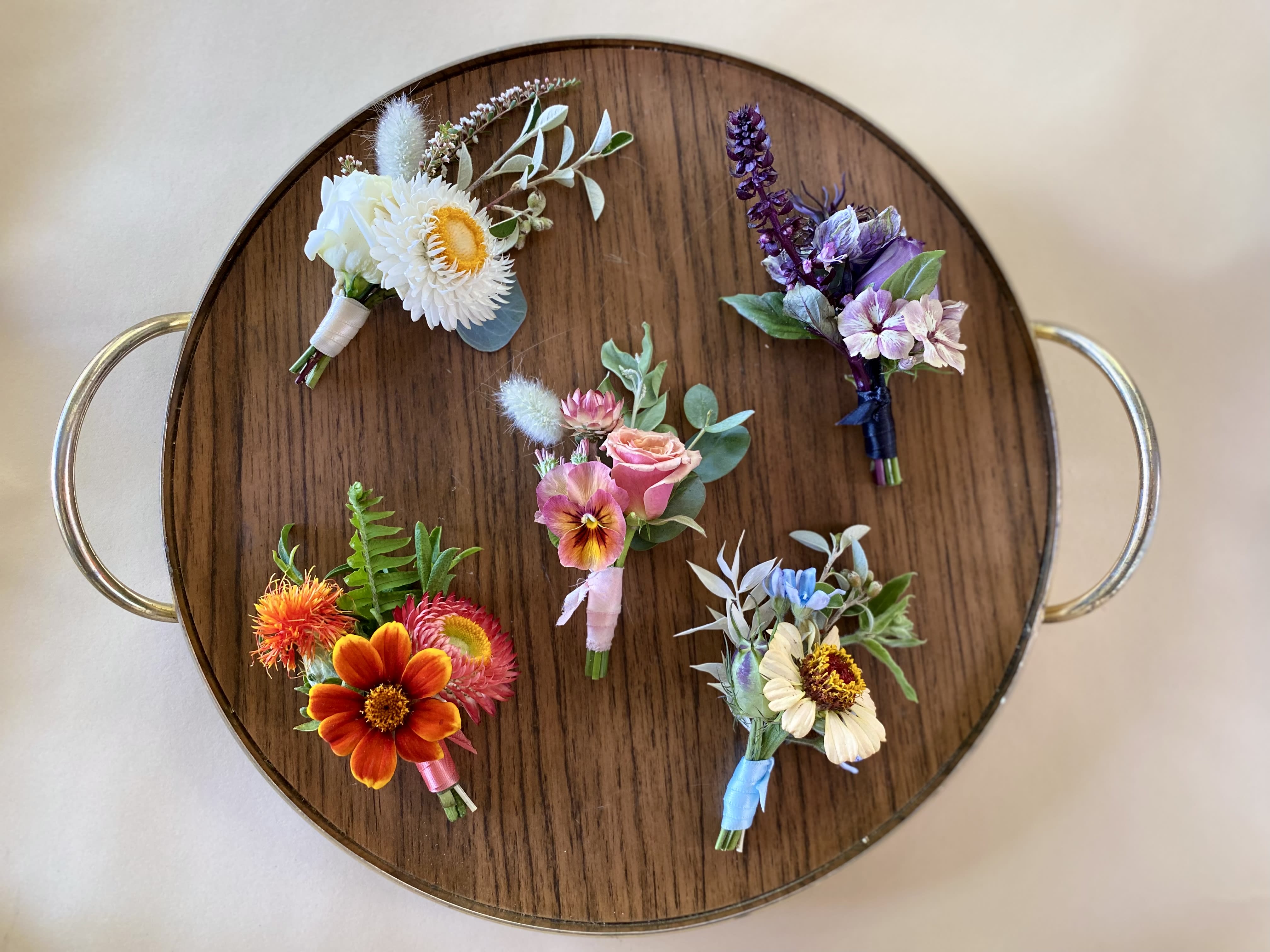 Boutonnière (adaptable color) - This is our classic Papillon boutonnière. We gather a fun, unique, and interesting selection of foliage and blooms and wrap them with a matching ribbon complete with pins to attach to clothing. These are wonderful for prom and other events.   When ordering, please leave us a note under “special instructions” with the desired color palette for your boutonnière.  This item is pickup only — please let us know in the notes what time you’ll be picking up. 