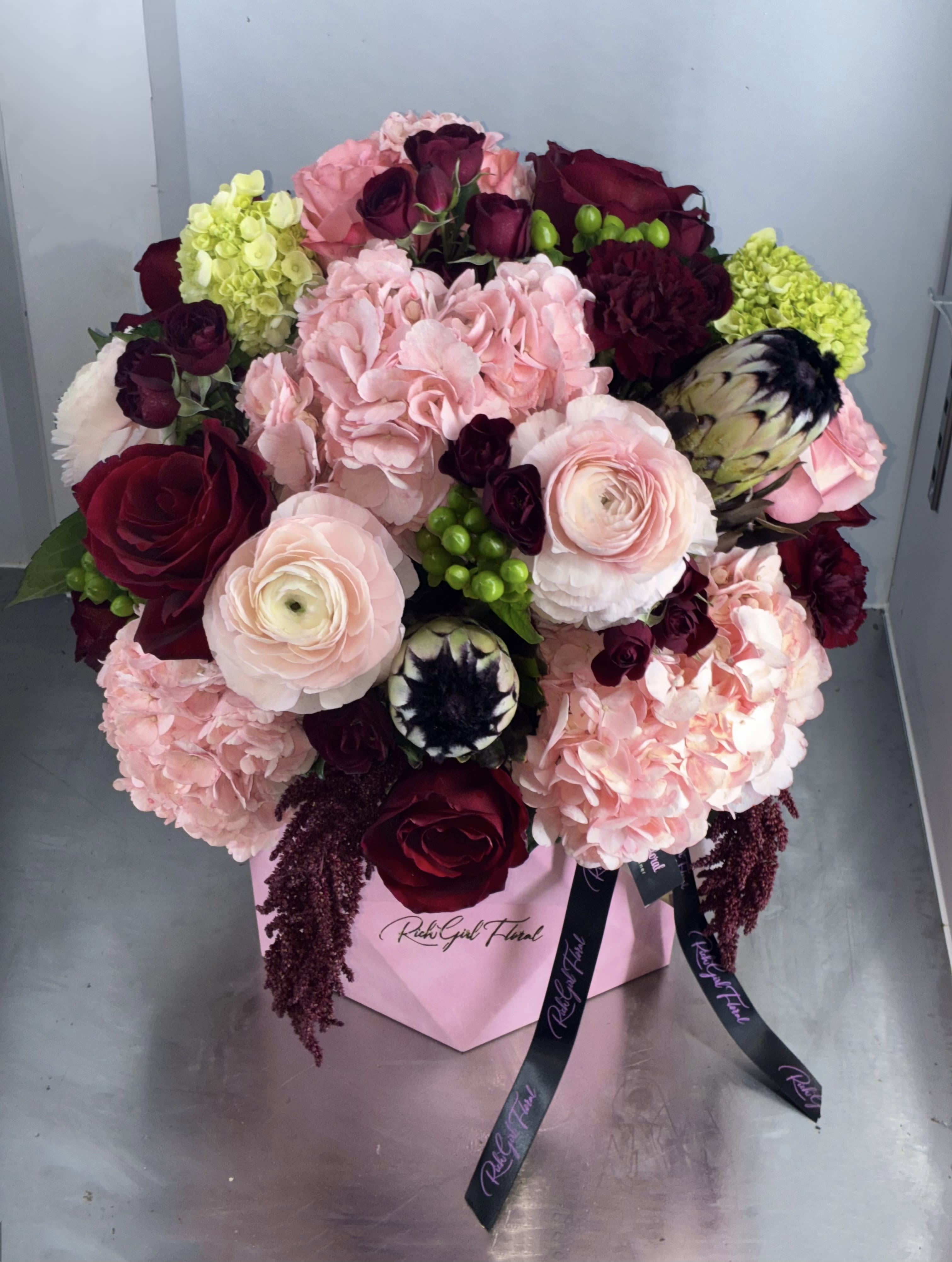 Love Spell Luxe Box - So lush! This luxe box features pink and red stems with green accent florals. The standard size includes one dozen premium roses. Upgrade to Deluxe for 2 dozen roses and Premium includes 2 dozen roses and premium accents stems such as peonies or orchids (depending on seasonal availability). 