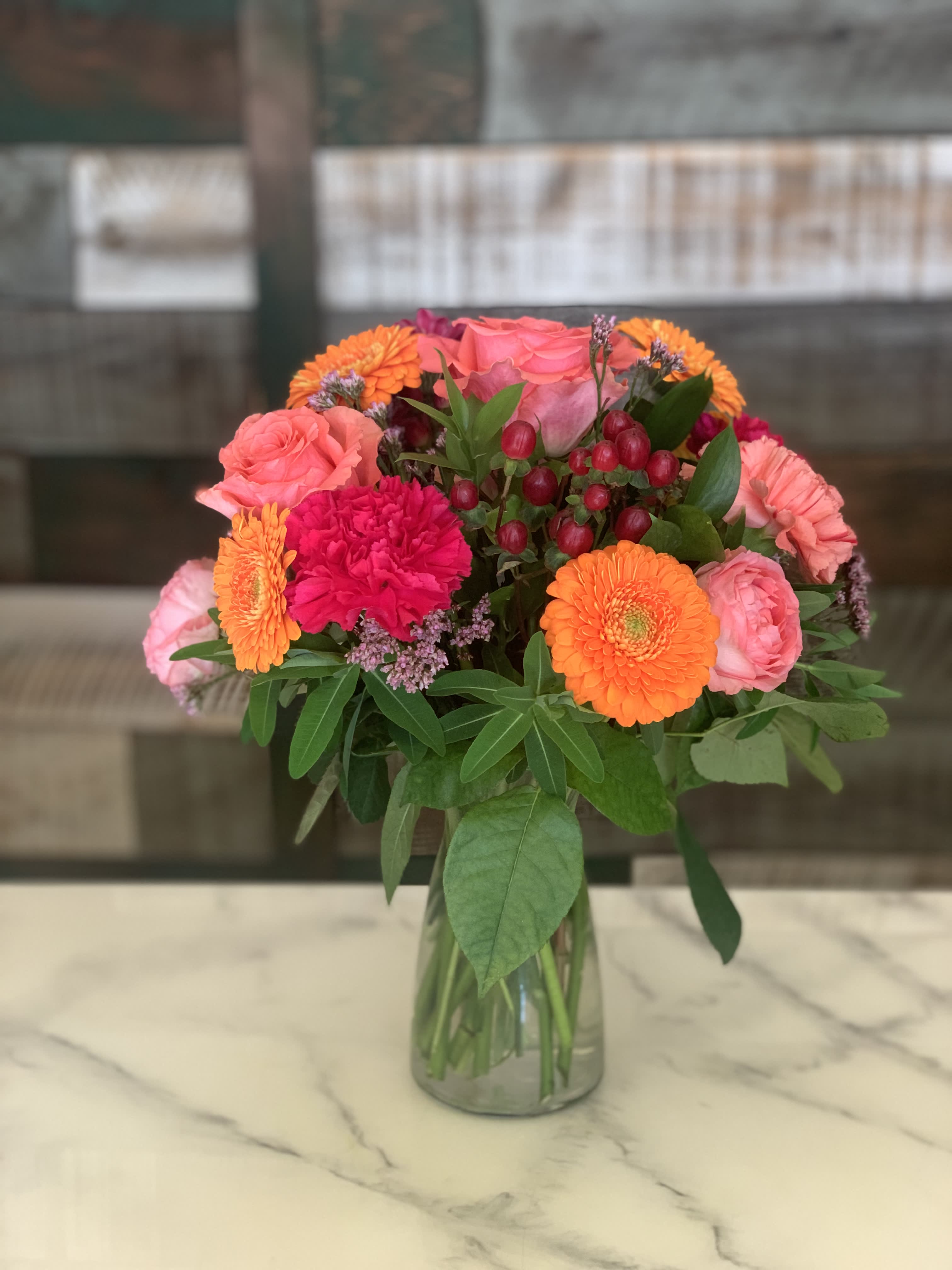 Jazzy Jazzy - This little jazzy bouquet is bursting with color! Roses, Spray Roses, Hypericum, Carns and Gerberas adorn this cute vase. This is perfect for a Birthday or any occasion. Approx. height and width 14" x 11" and colors vary