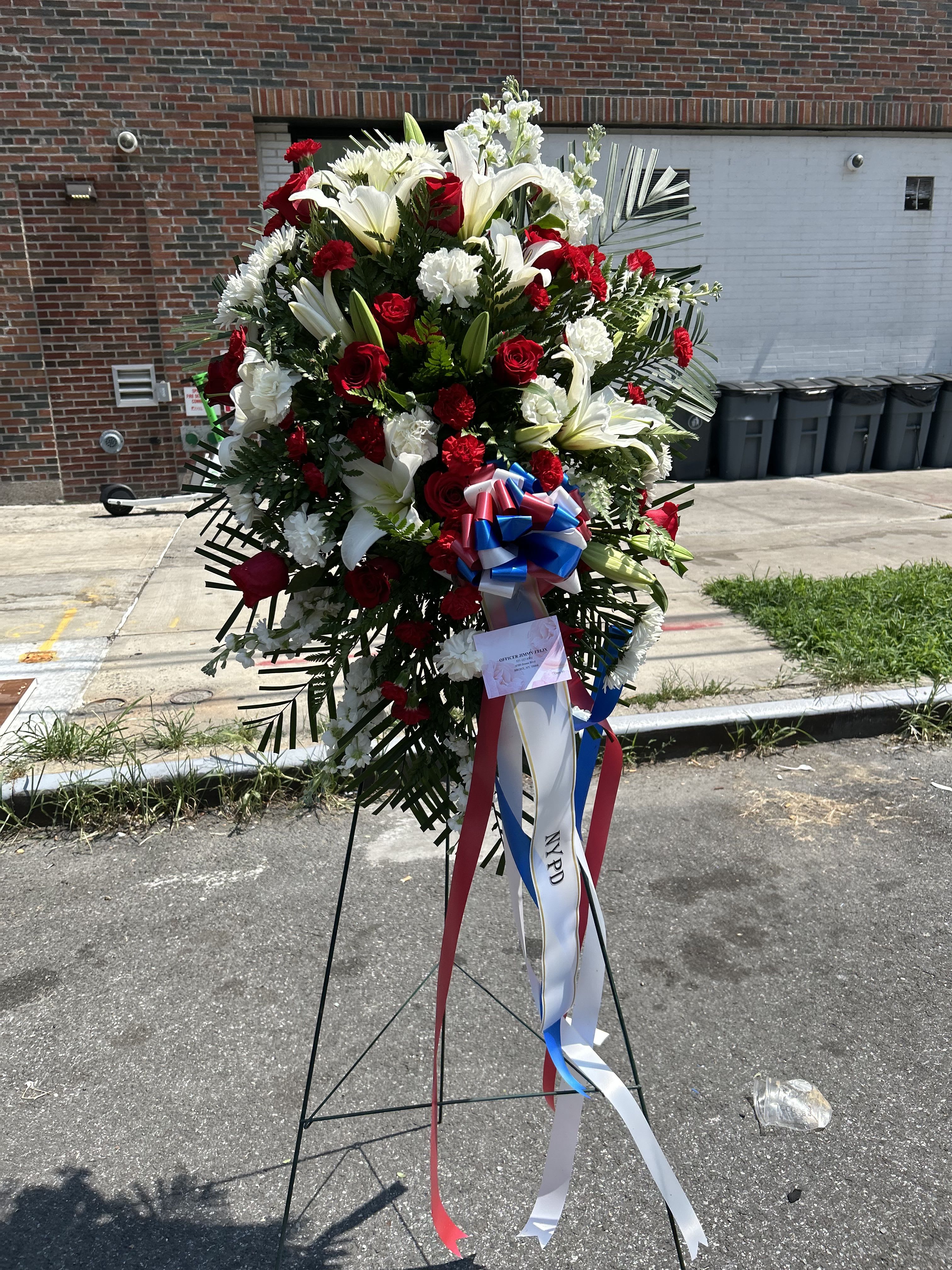Patriotic Standing Spray - Honor a veteran or a service member with our patriotic standing spray, a beautiful and dignified tribute. This arrangement is a heartfelt display of gratitude, symbolizing love of country, purity of spirit, and unwavering loyalty.