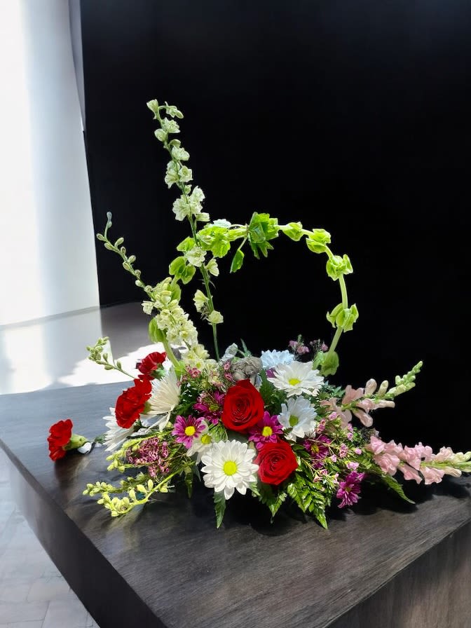 Comfort Angel Garden Seasonal Arrangement - This elegant arrangement includes our most beautiful flowers and a resting Angel keepsake  figurine. The angel measures roughly 3” wide by 5’” long and is 4” tall.  Please let our designers know your favorite flowers and colors, and we will do our best to ensure you send a perfect tribute.  Flower colors and types may vary due to availability, but we will try our hardest to accommodate your choices. 