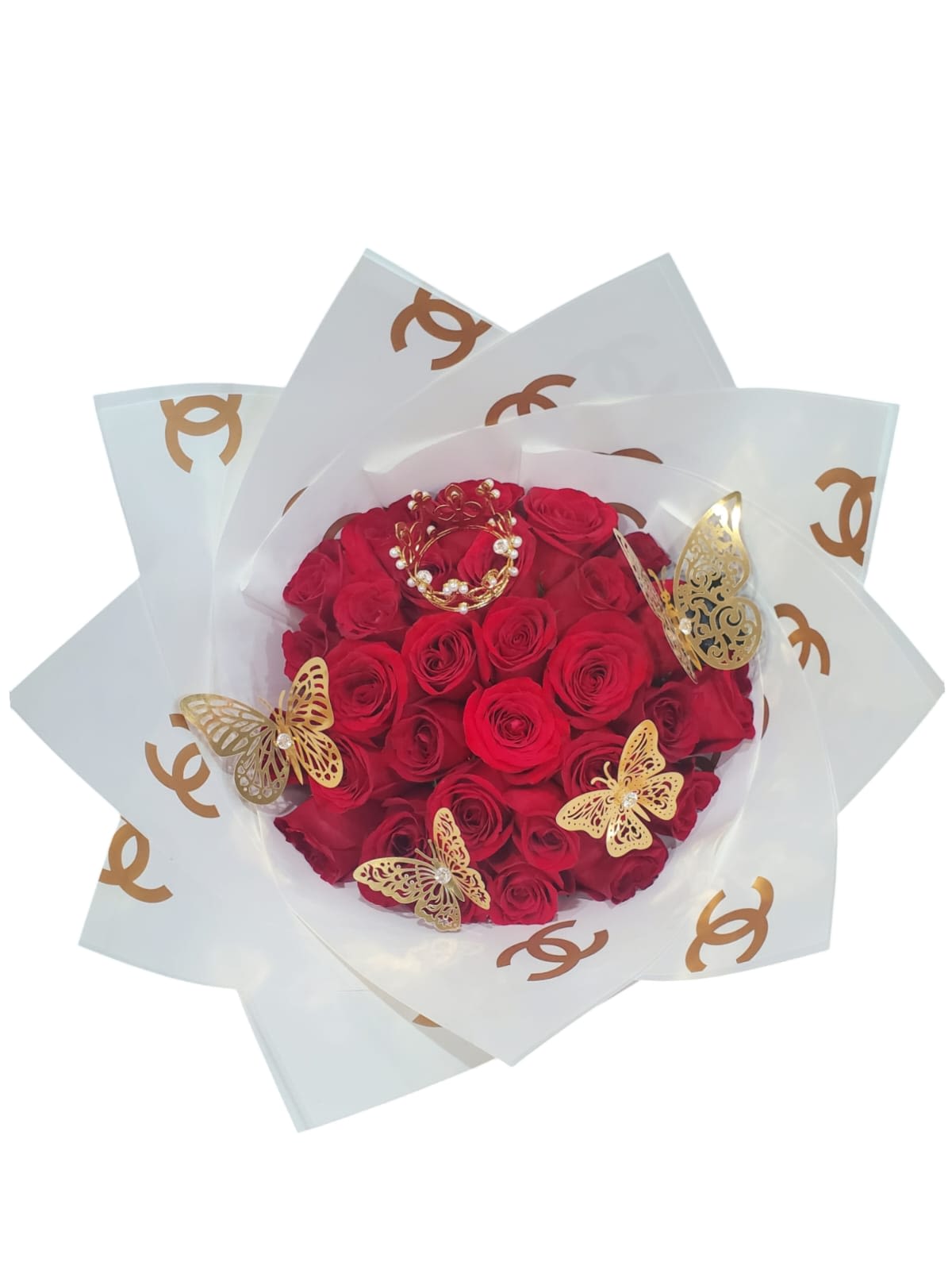 "Red Roses by Chanell" "Red Roses by Chanell" - Este arreglo floral es un diseño moderno y lujoso que combina rosas rojas, un toque de brillo con una corona pequena y mariposas doradas, y un envoltorio elegante con el icónico logo de Chanel.