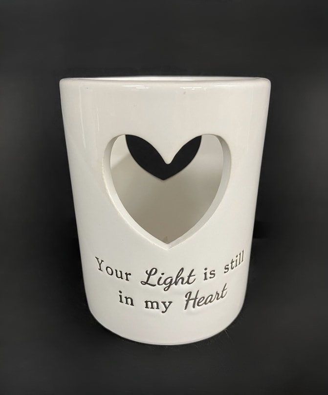 Your Light Is Still In My Heart Flickering Candle - &quot;Your Light is still in my Heart&quot; . This white ceramic candle measures 4&quot; wide by 5.5&quot; tall and includes a flickering tealight. Recommended as an accent in floral arrangements for many occasions. It can be purchased individually or with an accompanying floral arrangement (Deluxe).