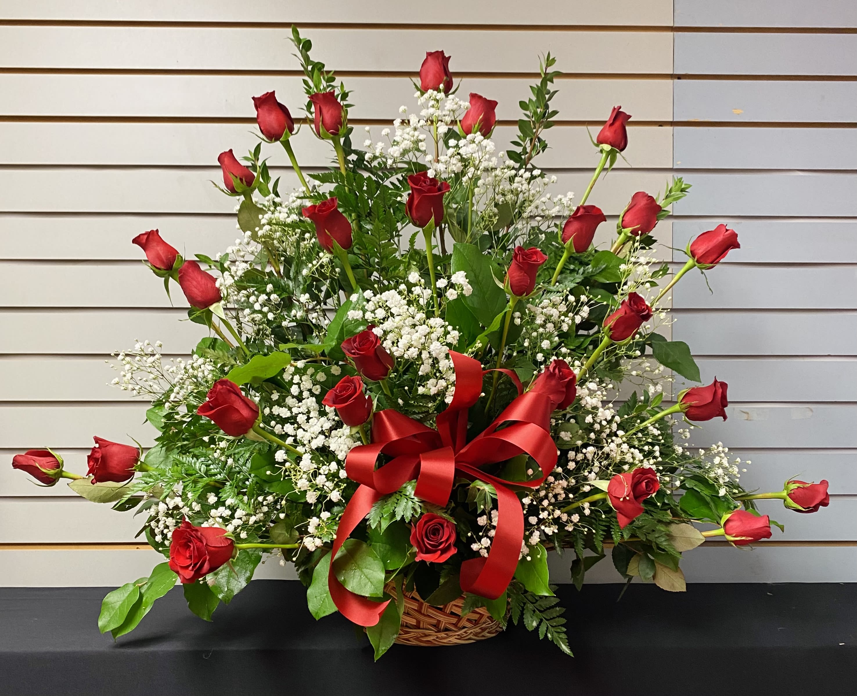 Red Roses in a basket Red Roses in a basket - Large and tall arrangement includes 24 Premium tall red roses artfully designed in a basket filled with baby's breath, mixed greenery garnished with a ribbon.
