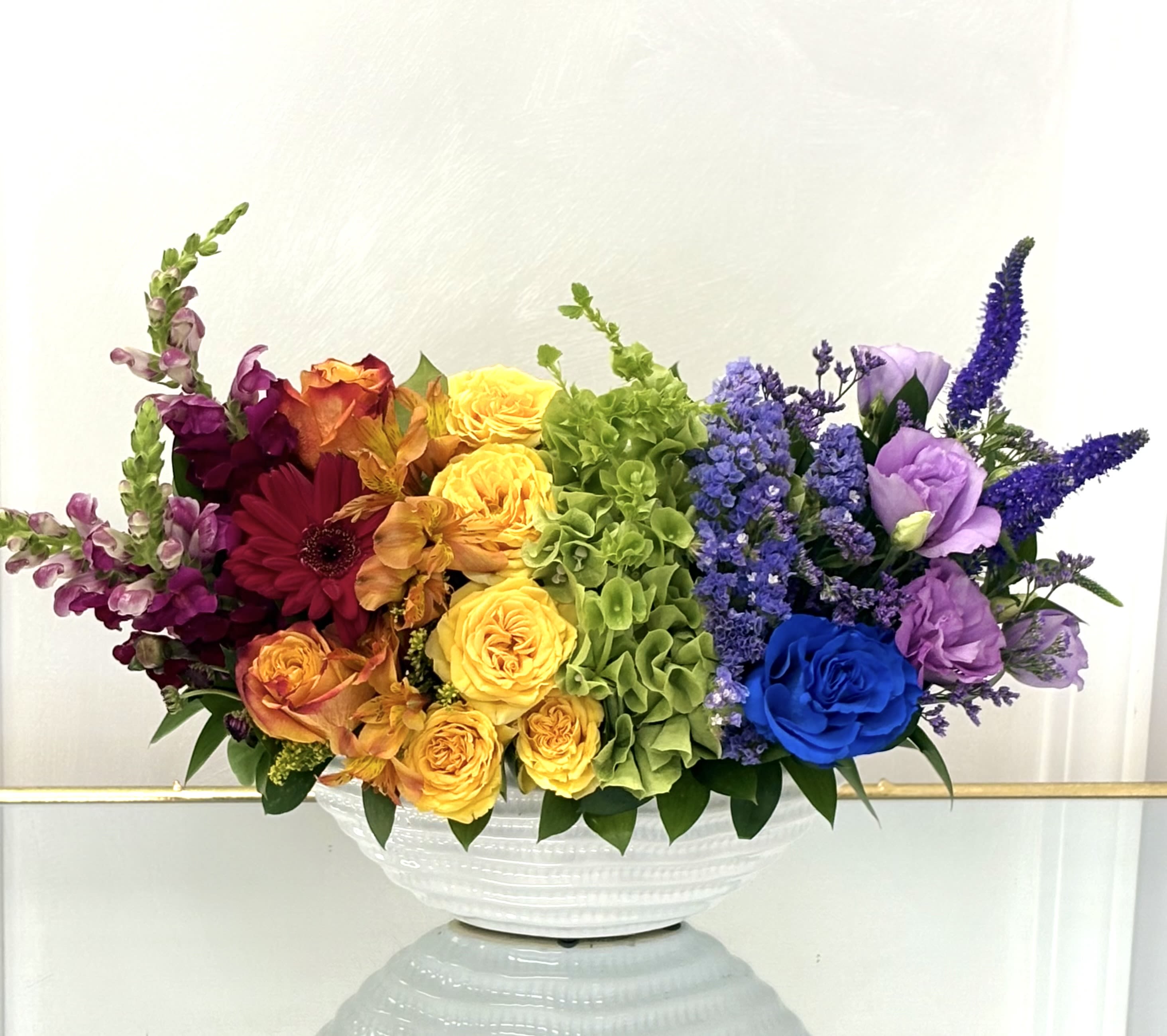 Color Symphony By VLM Flowers - A stunning celebration of every shade in the spectrum, Color Symphony features a bold mix of roses, snapdragons, lisianthus, and more. Arranged to flow like a rainbow, this vibrant display brings joy, energy, and harmony to any setting. Perfect for birthdays, pride celebrations, or simply brightening someone’s day.