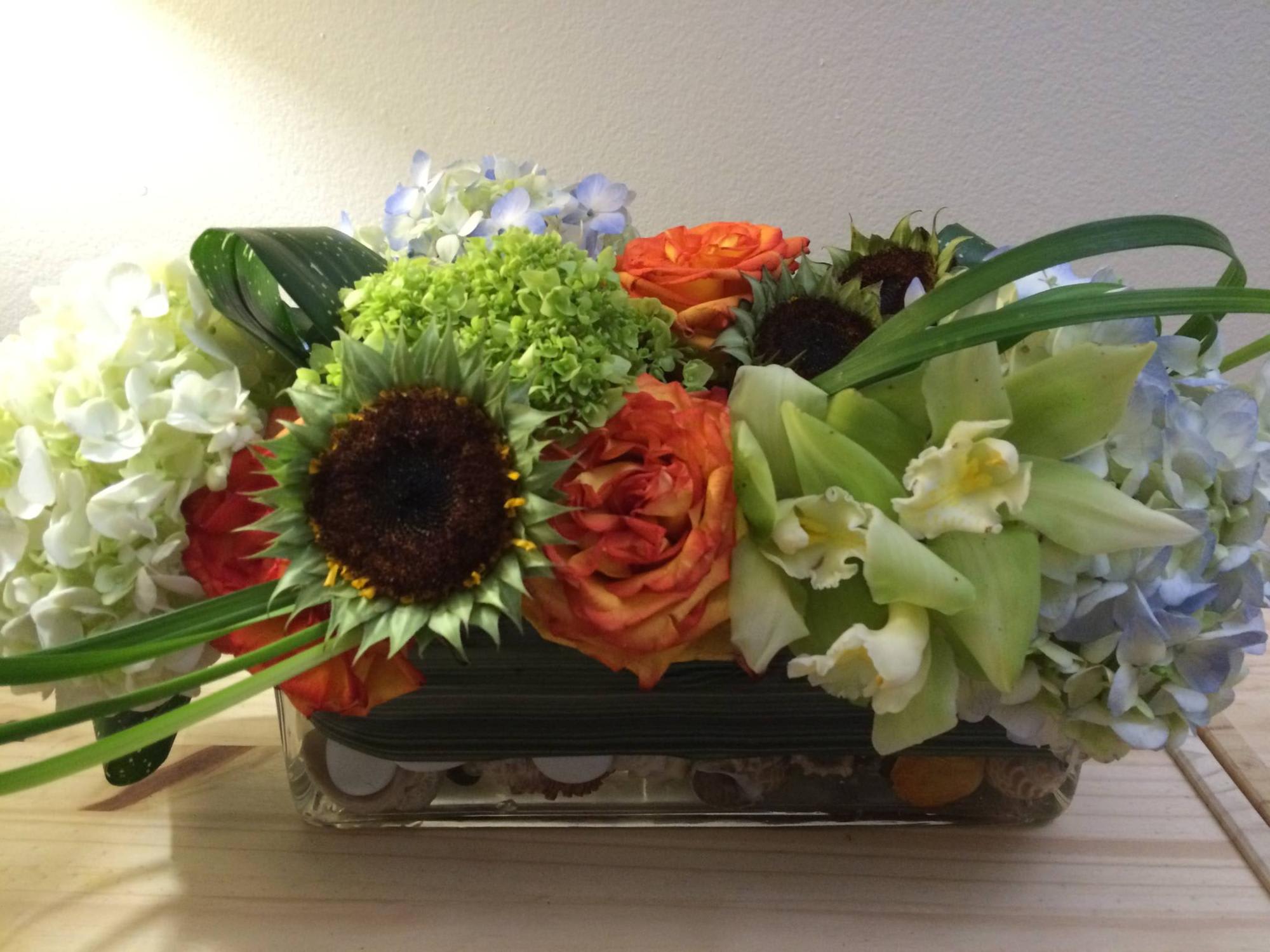 Natural Green Natural Green - Arrangement with white hydrangea, orange roses, and orchids.