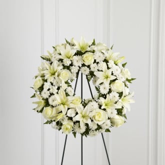 Treasured Tribute Treasured Tribute - The Treasured Tribute Wreath offers peaceful wishes of heartfelt sympathy with each delicate bloom. Bright white roses, Asiatic lilies, mini carnations and cushion poms are beautifully arranged to form an elegant accented with lush and vibrant greens. Displayed on a wire easel, this gorgeous tribute is a wonderful symbol of eternal life and sweet serenity. Approximately 18 inches in diameter.