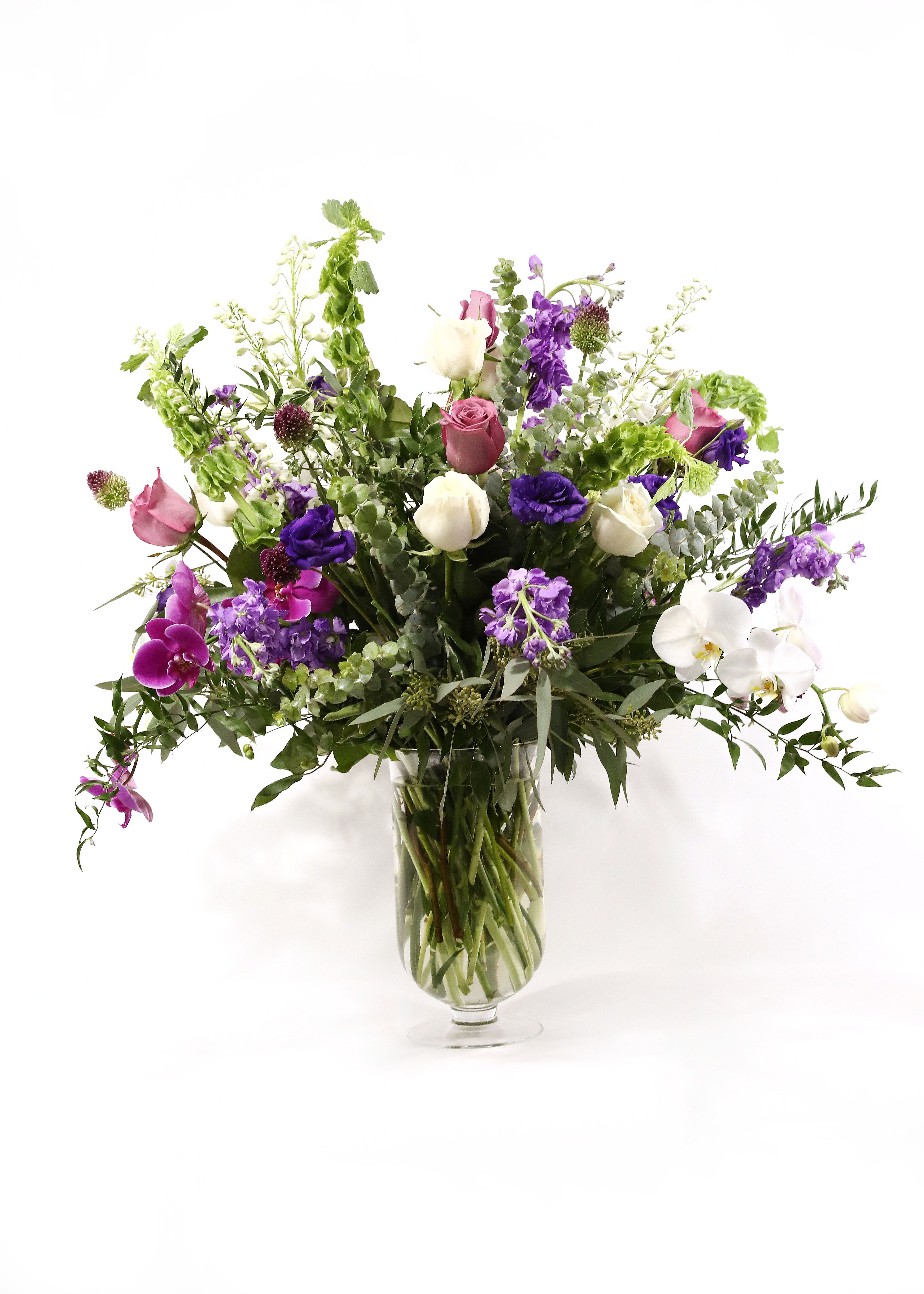 THE VIOLET QUEEN THE VIOLET QUEEN - THIS QUEEN HAS BELLS OF IRELAND, CYMBIDIUM ORCHIDS, ROSES, STOCK, ALLIUM, DELPHINIUM, AND LISIANTHUS IN A CLEAR TALL VASE.
