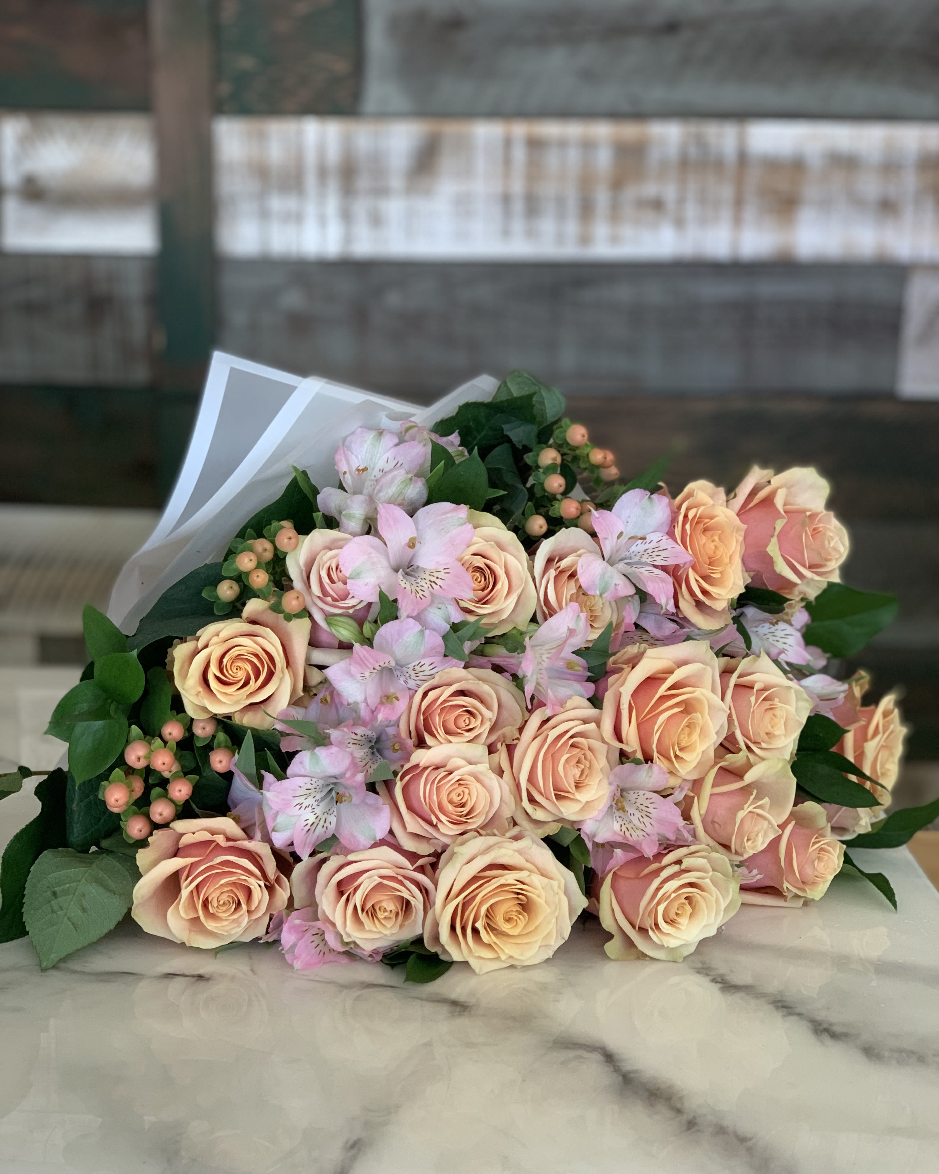 Above the Grade Wrapped Roses Above the Grade Wrapped Roses - A bountiful bouquet of 18 roses with assorted filler and greenery wrapped to perfection for your loved one. Colors vary based on availability.