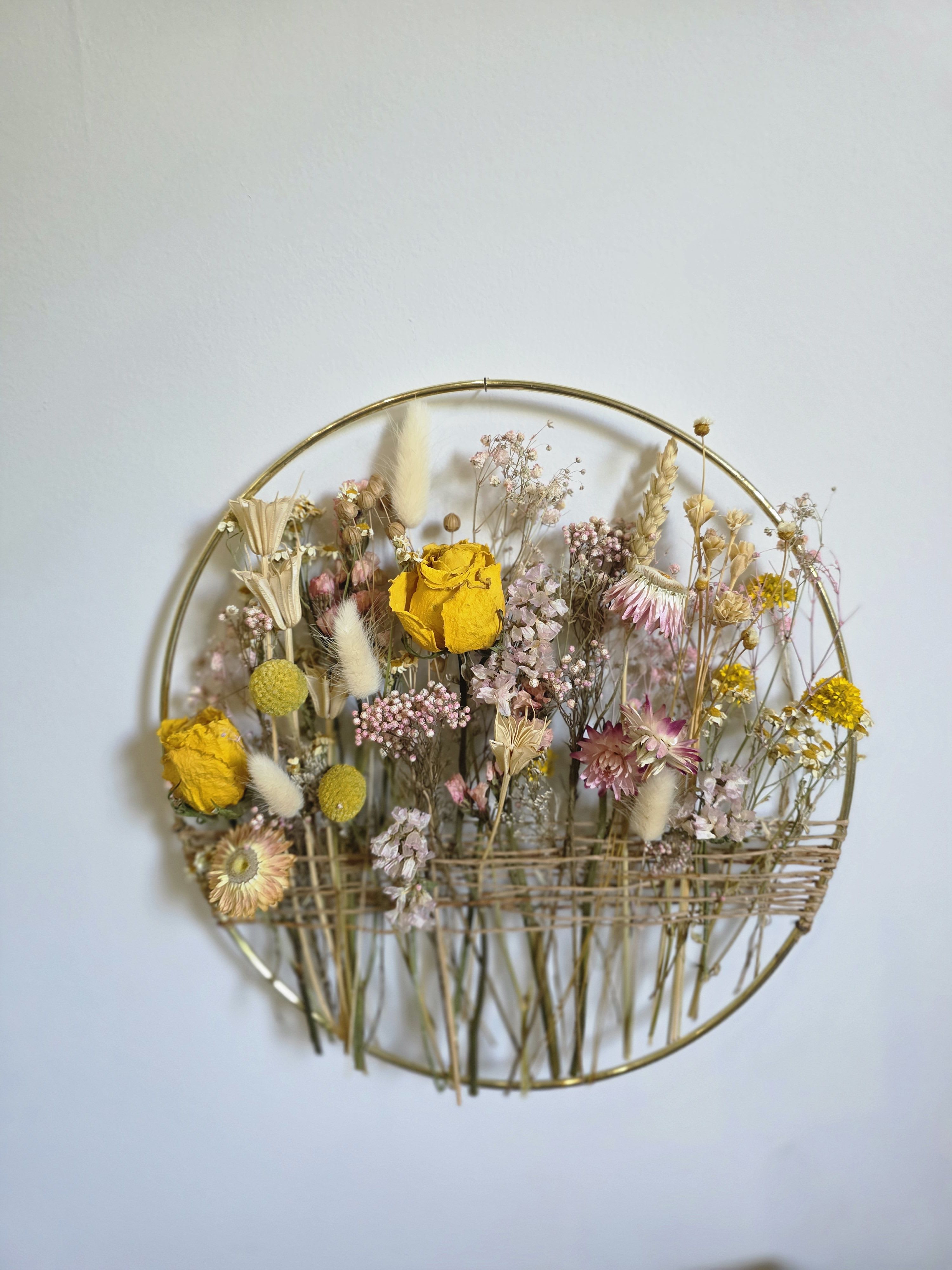 Dried Flower Hoop Wall Hanging Dried Flower Hoop Wall Hanging - Add a touch of natural elegance to your space with our Dried Flower Hoop Wall Hanging. Featuring a minimalist gold hoop adorned with carefully arranged dried blooms and foliage, this piece blends rustic charm with modern simplicity. Perfect for nurseries, entryways, or dorm walls, it brings lasting beauty and texture to any room—no upkeep needed. Colors may vary