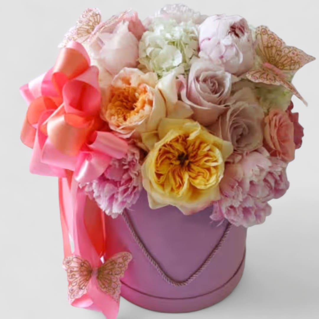 Rosie Flower Box - Roses of mixed shades and styles of pinks lavenders and blush arranged in a large pink velvet flower hat box. Simply stunning! Tall and adorned with a long pink and blush satin ribbon bow with blush fairy dust butterflies. Perfect to send for every occasion to show them how much you care. All of my bouquet designs are always made extra special and unique each and every time. Please visit my beautiful gallery to see my most recent designs that I have created for my online customers. Send them lots of happiness. Order yours now.