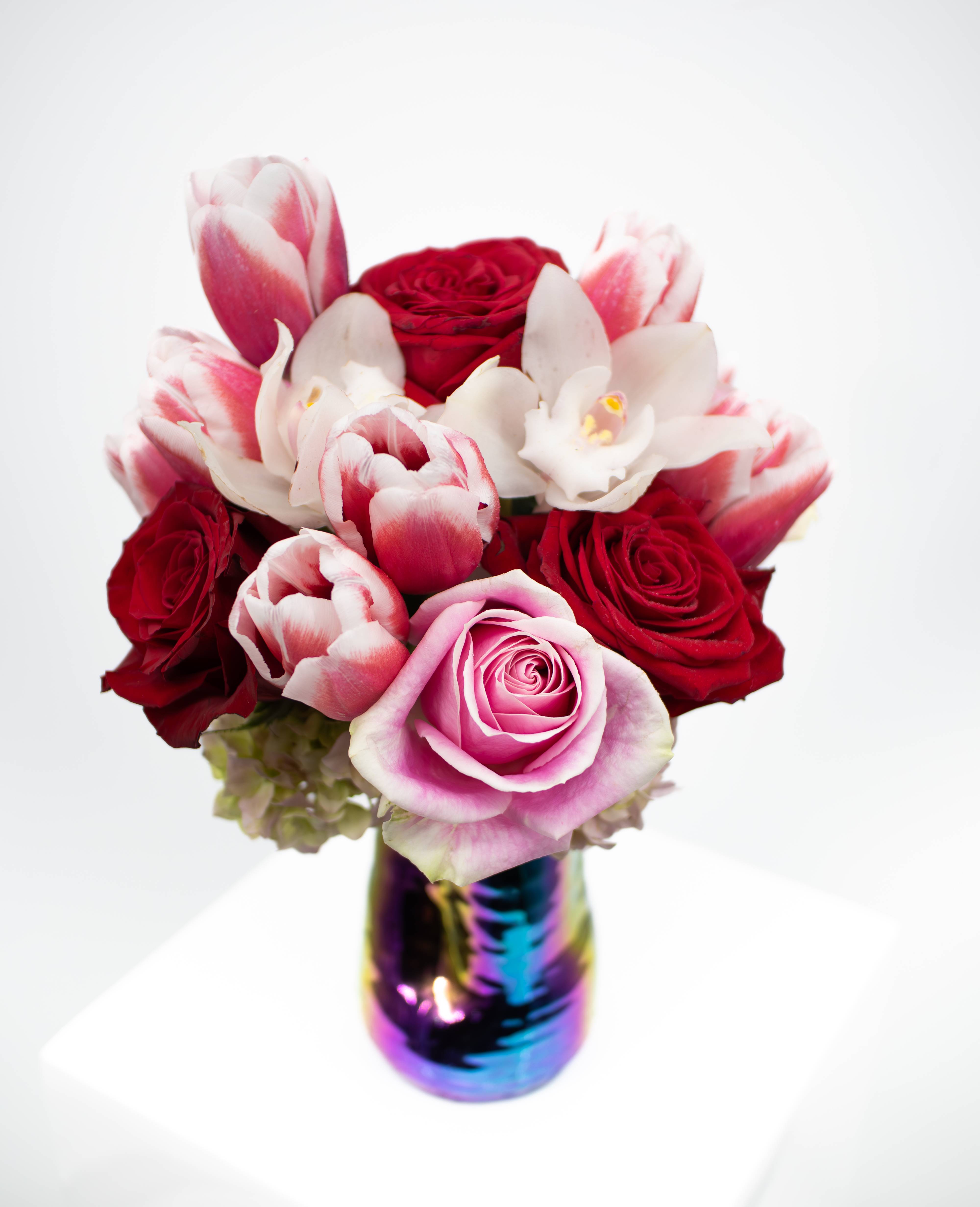 Stella Stella - Introducing Stella, a breathtaking fusion of elegance and vibrancy. Delicate roses, exotic orchids, graceful tulips, and lush hydrangea come together in a stunning array of colors, perfectly complemented by our captivating rainbow vase. Each bloom radiates its unique charm, creating a symphony of beauty that captivates the senses. Elevate any space with this exquisite arrangement.
