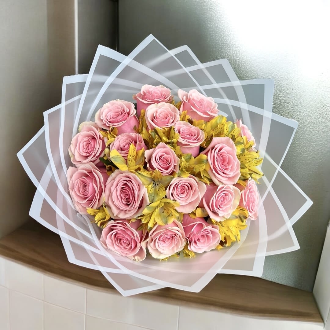 Sunset Blush Bouquet  - A delicate and vibrant bouquet featuring soft pink roses paired with cheerful yellow alstroemeria. Wrapped in elegant translucent layers, this arrangement is perfect for celebrating love, friendship, or simply brightening someone’s day with a touch of warmth and grace. BOUQUET HAS APPOX. 18 ROSES (deluxe and premium will increase the quantity of roses)   Un ramo delicado y vibrante con suaves rosas rosadas combinadas con alegres alstroemerias amarillas. Envuelto en capas translúcidas elegantes, este arreglo es perfecto para celebrar el amor, la amistad o simplemente alegrar el día con un toque de calidez y elegancia. 