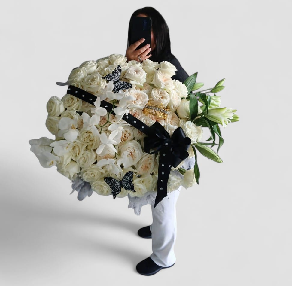Vanilla Grande Bouquet - Grande 5 dozen white roses with orchids and lilies arranged with black ribbon and wrap. Stunning. Send an impressive bouquet to show them how much you care.