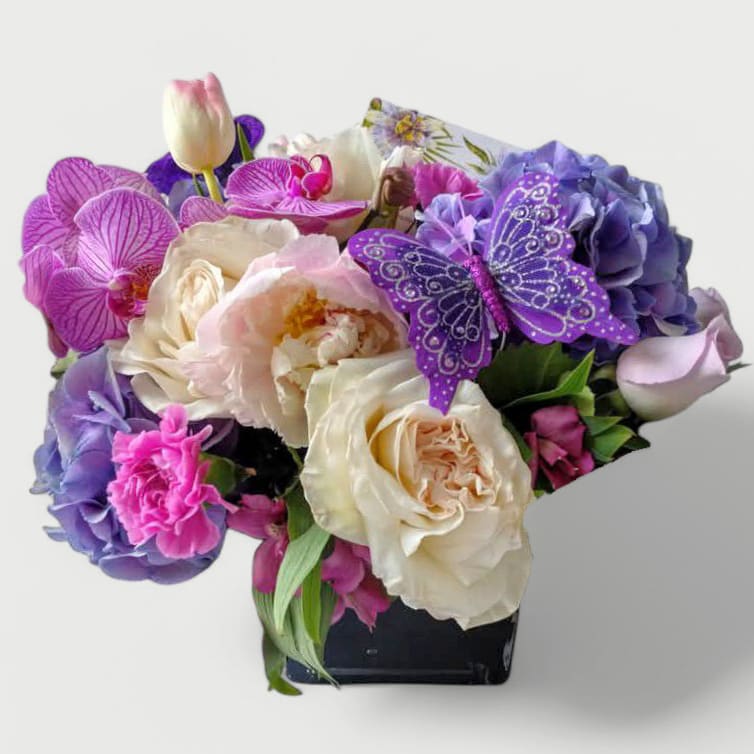 Condolences Purple Blossom Beauty Designer's Choice Condolences Purple Blossom Beauty Designer's Choice - Beautiful purple blossom selection of that day roses orchids and more arranged in a modern glass cube vase. Perfect to send as a condolences. All fresh flower bouquets that leave my flower shop studio are made beautiful and special each time. Please visit my beautiful gallery to see my latest designs that I created for my online customers. Send them you deepest condolences.