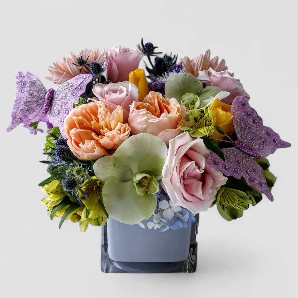 Sending A Hug Bouquet Designer's Choice - Beautiful bouquet filled with blush mint and lavender blossoms arranged in a modern grey blue glass vase. Send happiness today.