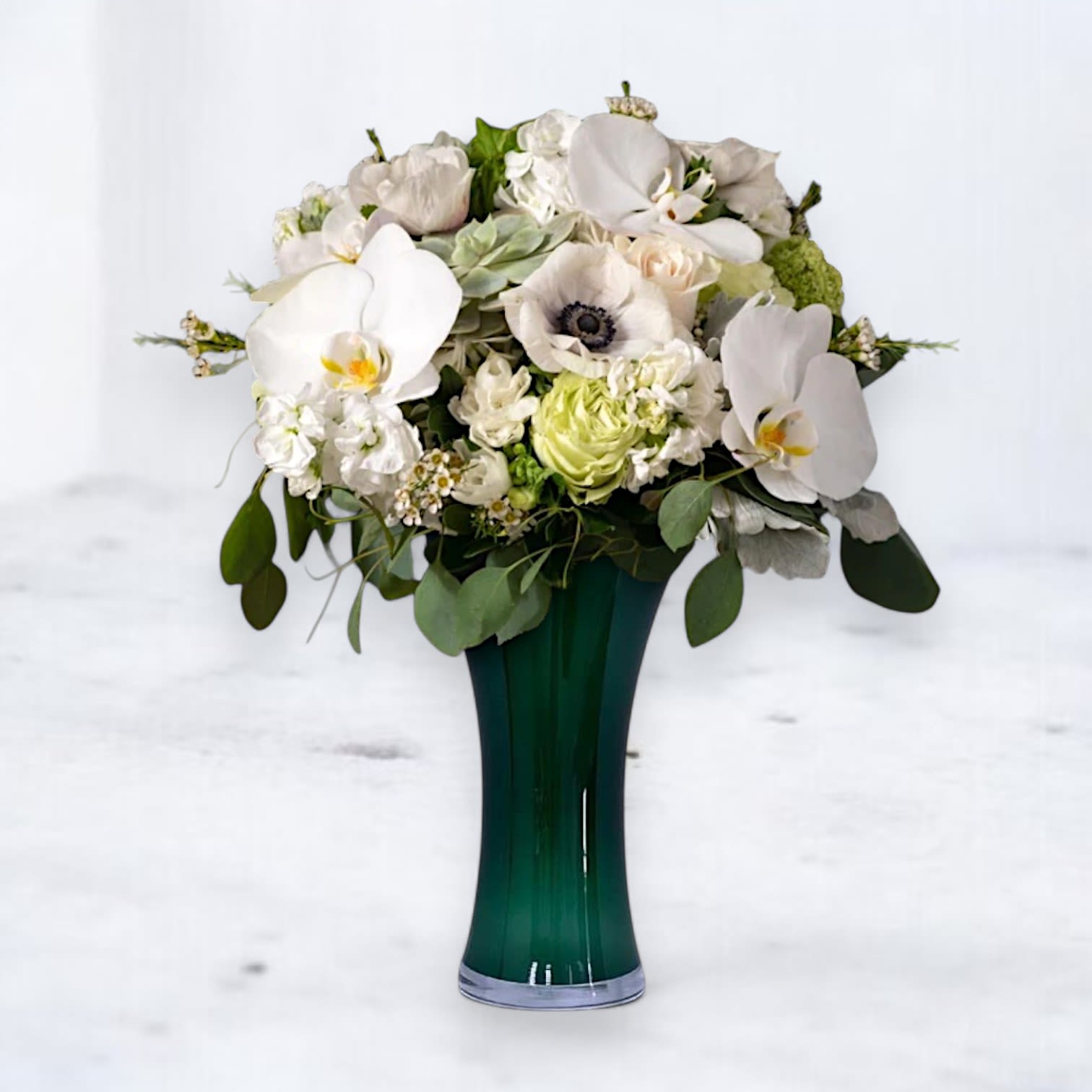 Heavenly Haven Bouquet - The Heavenly Haven Bouquet is a graceful blend of pure white orchids, delicate anemones, soft stock, and lush green roses, beautifully arranged in a sleek 10&quot; tall dark green vase. This serene design symbolizes peace, comfort, and cherished remembrance, making it a meaningful tribute for sympathy occasions or to honor a life well-lived.  Why You'll Love It: Features premium blooms like Phalaenopsis orchids and anemones for an elegant touch. Soft white and green tones offer a calming, heartfelt sentiment. A timeless arrangement perfect for memorials, sympathy gestures, or thoughtful remembrance. 