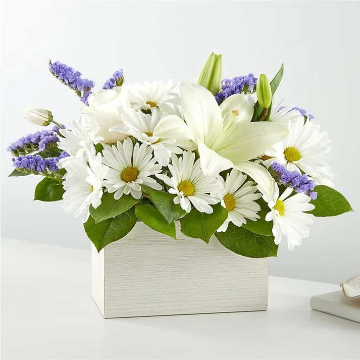 Beyond Blue Box Bouquet  - Channeling calmness and serenity our Beyond Blue Box Bouquet features white blooms complemented by pops of purple. This beautiful arrangement is designed with daisies, roses, and lilies. Details The Deluxe Bouquet is approximately 12&quot; H x 15&quot; W.