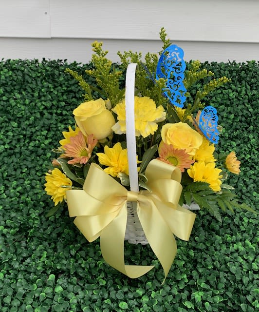 Yellow Sympathy Basket - A sympathy basket brimming with roses and flowers carries an unspoken elegance and heartfelt warmth. Basket Details Container: A woven wicker basket in soft natural tones, perhaps with a satin ribbon tied neatly to the handle.  Arrangement Style: Gracefully fanned out, the flowers are layered to show dimension, with taller stems at the center and cascades near the edge.  Accent Elements: A small card tucked into the blooms with a gentle note of condolence, and perhaps a sheer drape of organza or lace for a finishing touch.  This kind of arrangement quietly says “I’m thinking of you” and brings a moment of beauty to someone’s grief. If you'd like suggestions for wording the card or want ideas tailored to a specific person or occasion, we would be honored to help.