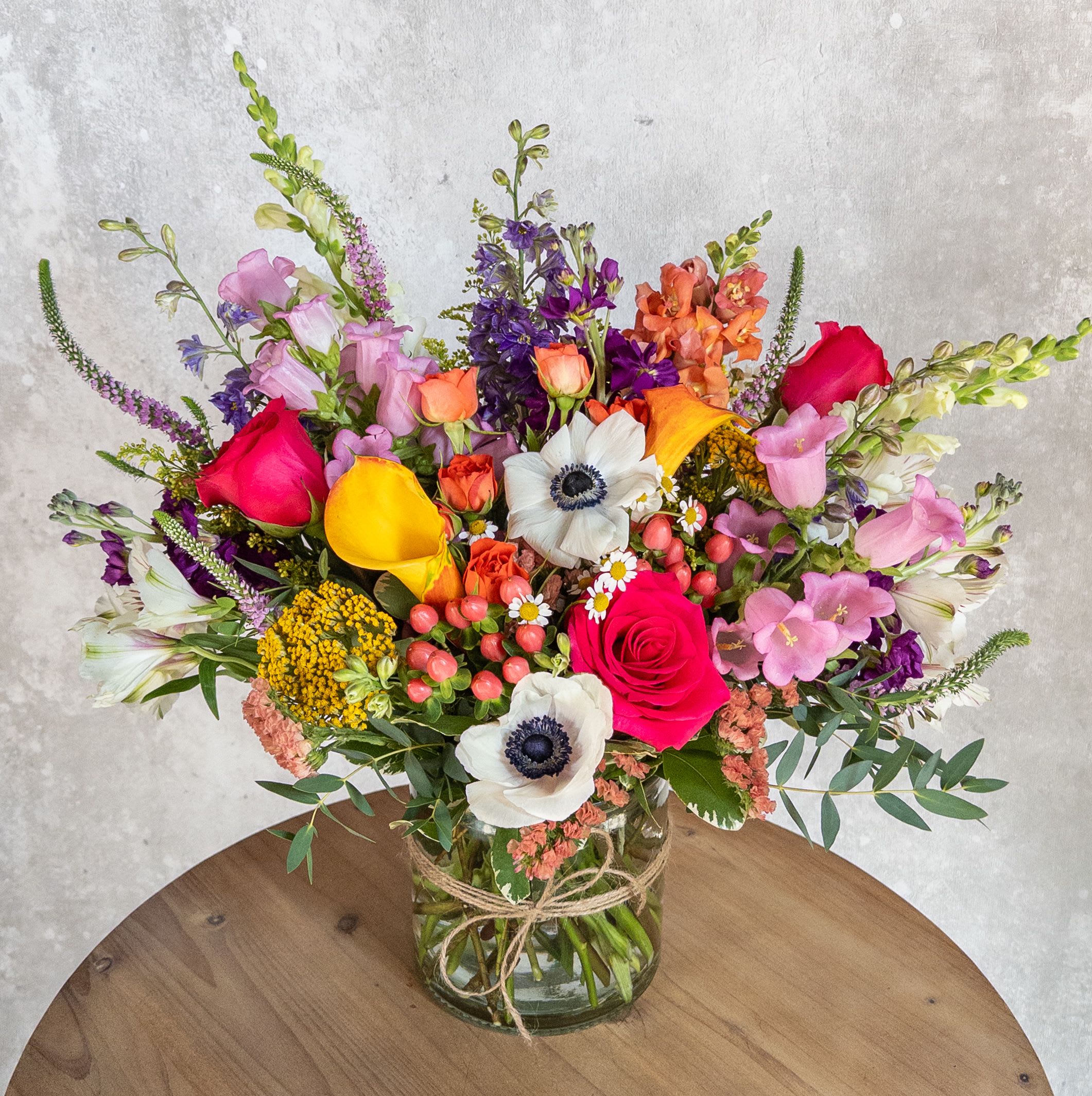 Wildflower love  - A wide clear glass cylinder filled with a lot of color and texture! A beautiful mix of a variety of flowers, snapdragons, roses, and anemones to name a few. Bright, wild and fun! 