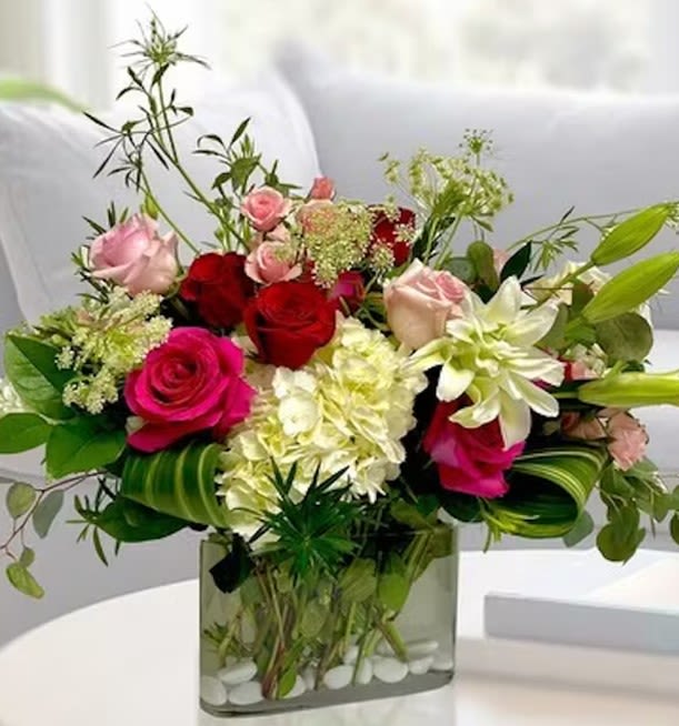 Delightful Romance - This stunningly romantic bouquet is sure to delight and brighten anyone's day. Featuring Hot Pink Rose, Freedoms, Rose Lilies, Spray Roses, Queen Anne, Hydrangea, pink Roses, Aspidistra and Eucalyptus in a clear glass vase. 