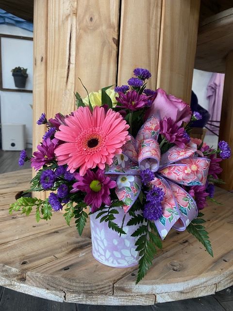 Spring is in the Air Spring is in the Air - A Short Arrangement featuring various colored flowers in the spirit of spring! Bouquet is set in a metal container in the colors of pink, purple or green if you have a specific color please let me know!
