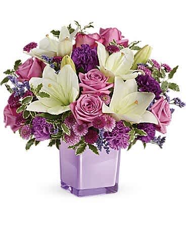 Teleflora's Pleasing Purple Bouquet Teleflora's Pleasing Purple Bouquet - These luxurious lavender roses and crisp white lilies are poised to please! Perfectly presented in a stylish cube vase, it's an any-occasion surprise they'll never forget! Lavender roses, white asiatic lilies, purple carnations, lavender carnations, purple button spray chrysanthemums and lavender button spray chrysanthemums are arranged with lavender limonium and pitta negra. Delivered in a glass cube.