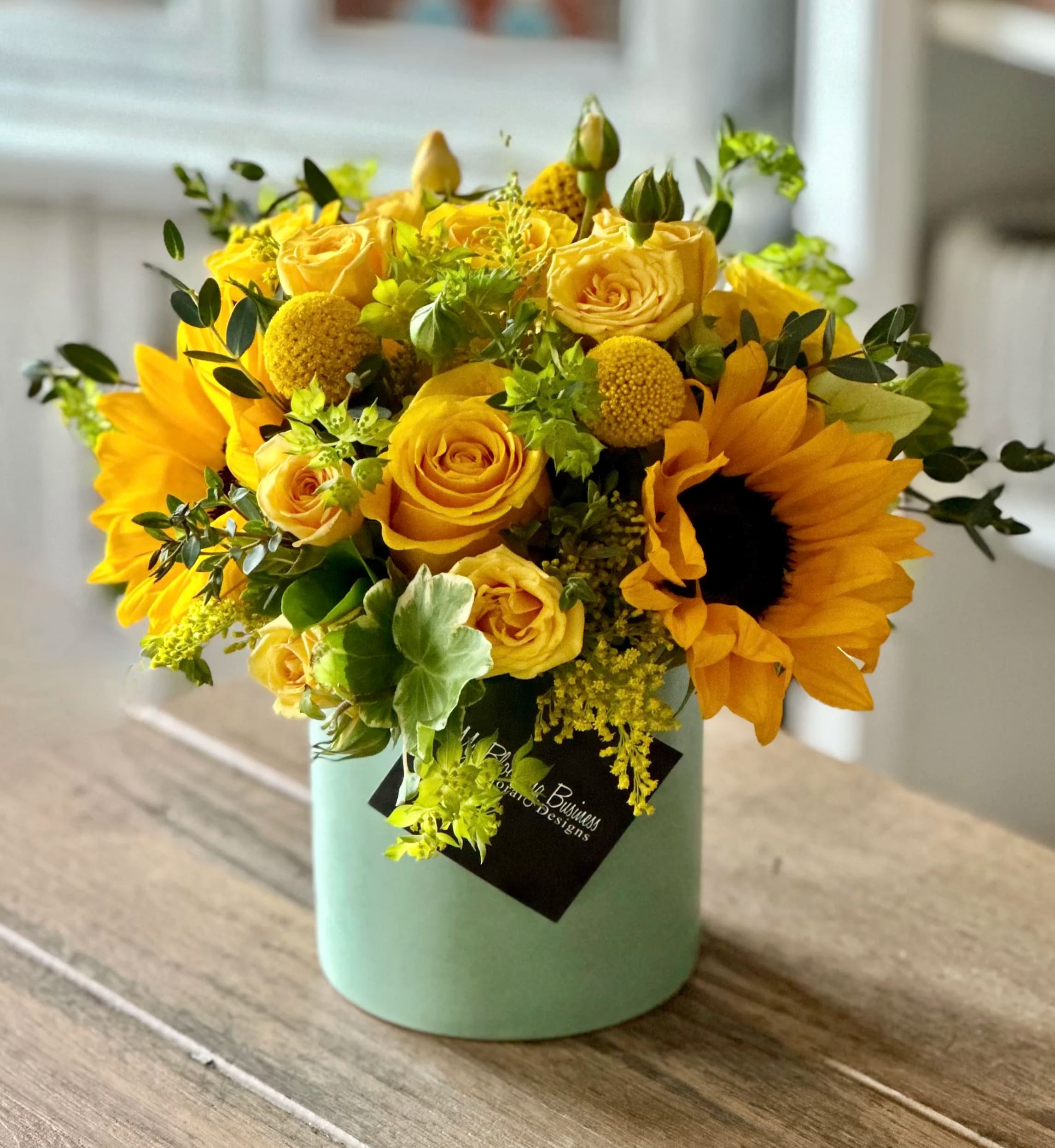 Little Miss Sunshine  - The Little Miss Sunshine arrangement is the perfect way to capture the joy and spirit of summer in your home or office. This elegant vase arrangement contains vibrant yellow roses, sunflowers and other seasonal flowers which will light up any dull corner. The bright mint green container adds a lovely contrast to the cheerful arrangement of blooms. With its casually classic presentation, The Little Miss Sunshine is ideal for a wide range of occasions and settings. Whether it's a housewarming gift, an elegant salon center piece, or just something to sweeten up your day, this unique flower arrangement is sure to do the trick!