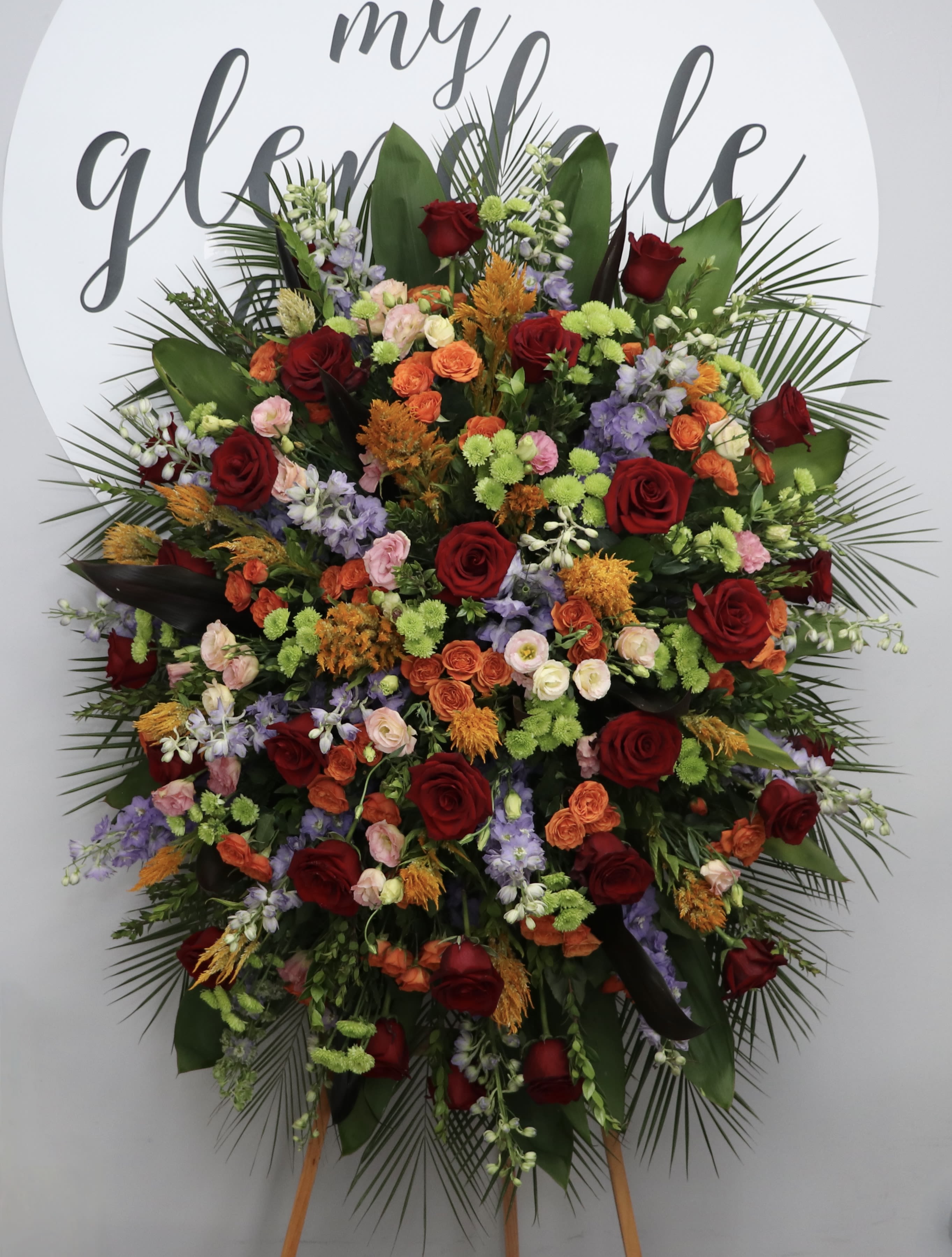 Eternal Flame  - With bright multi-toned roses, snapdragons and seasonal greens, this sympathy arrangement stands at approximately 30 inches tall. Deluxe and Premium sizes are also available, measuring approximately 36 and 42 inches respectively. 